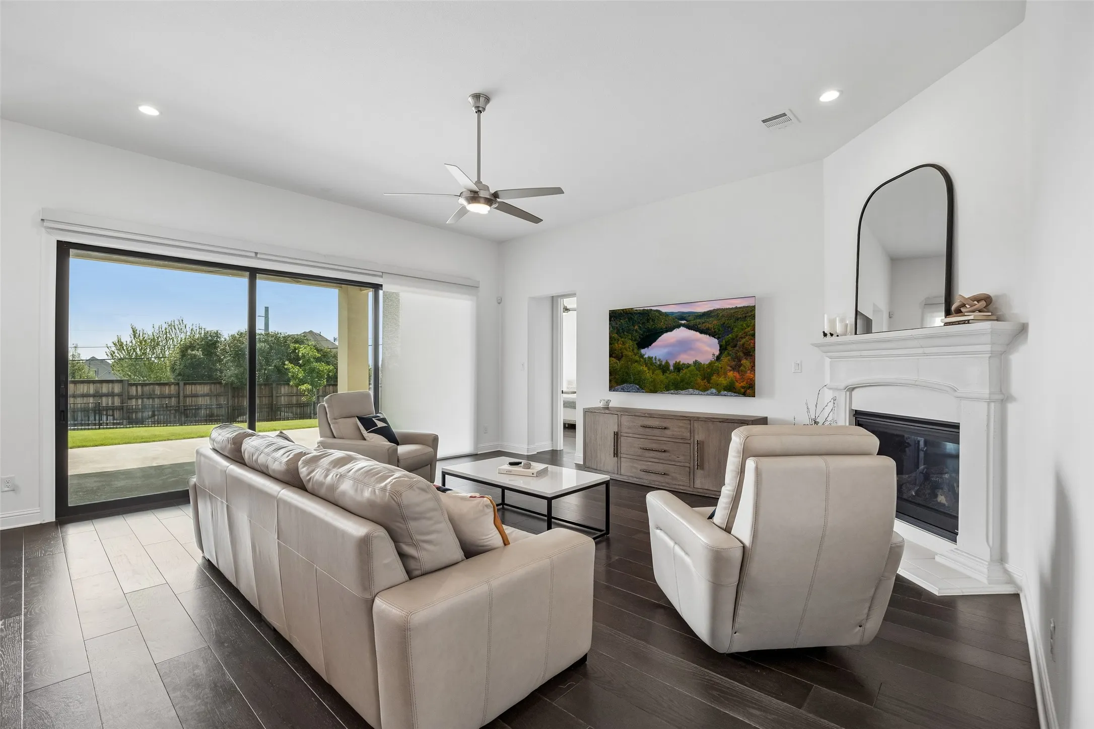 Spacious living area featuring dark wood-finish flooring and white walls