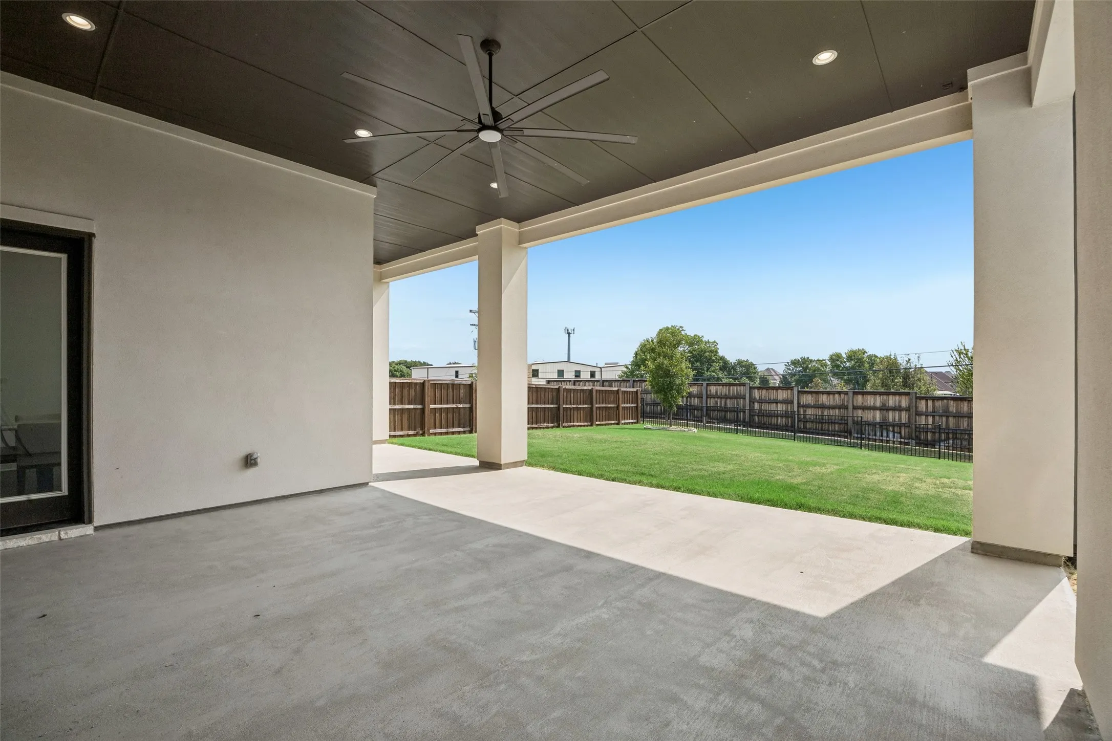 Covered concrete patio with a dark wood-finish ceiling and recessed lighting