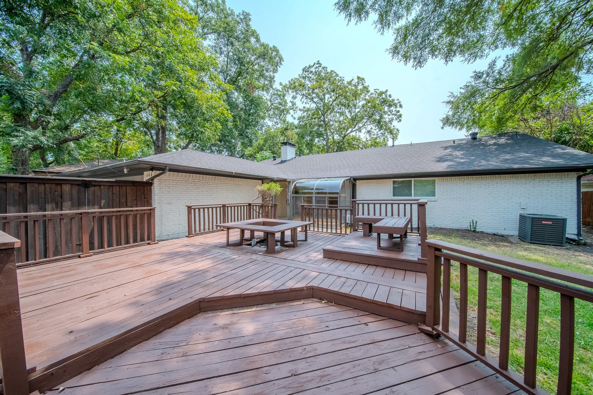 Multi-level wood deck featuring built-in seating, a square fire pit, and wood railings