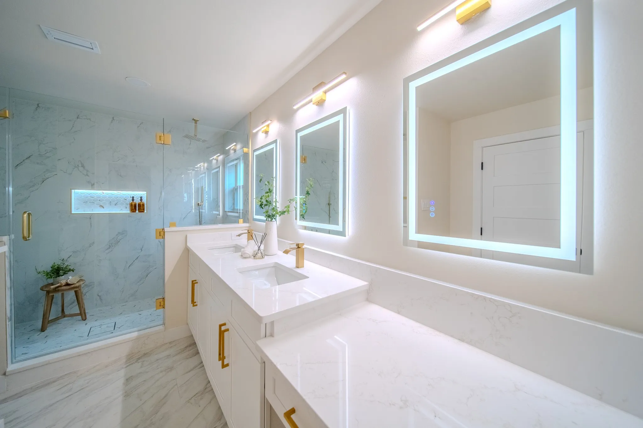 Dual vanity with integrated sinks and white countertops, accented by gold-finish hardware and fixtures