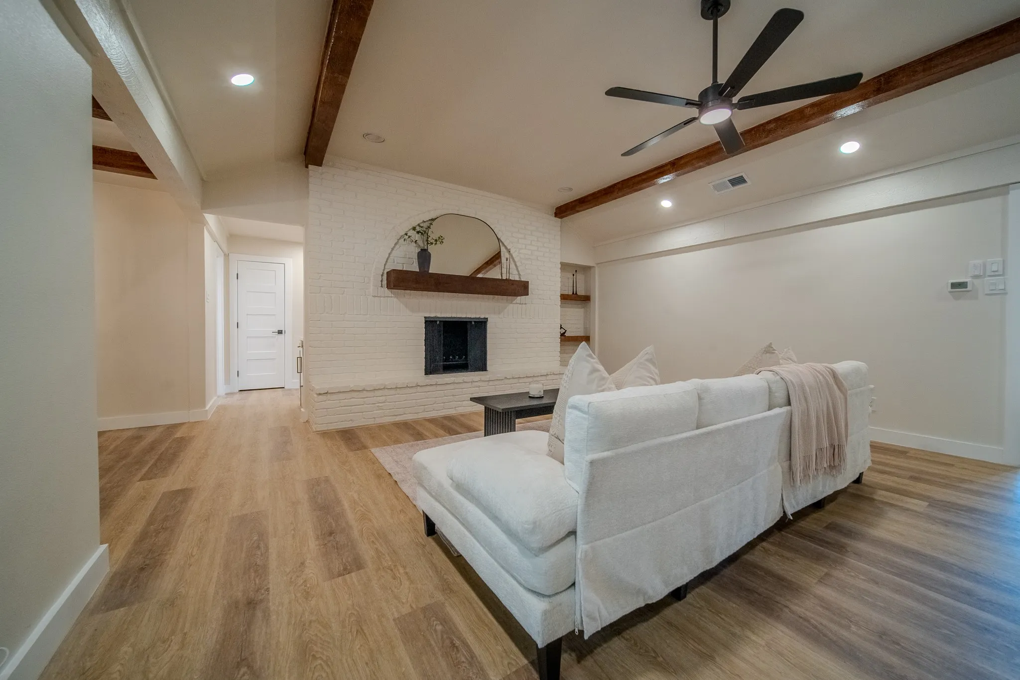 Wood-finish flooring throughout, featuring a white brick fireplace with a wood mantel