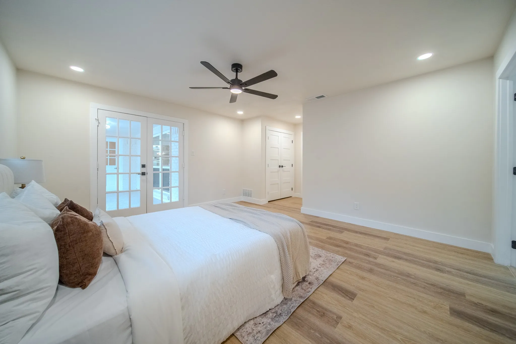 Wood-finish flooring, recessed lighting, ceiling fan, and white French doors