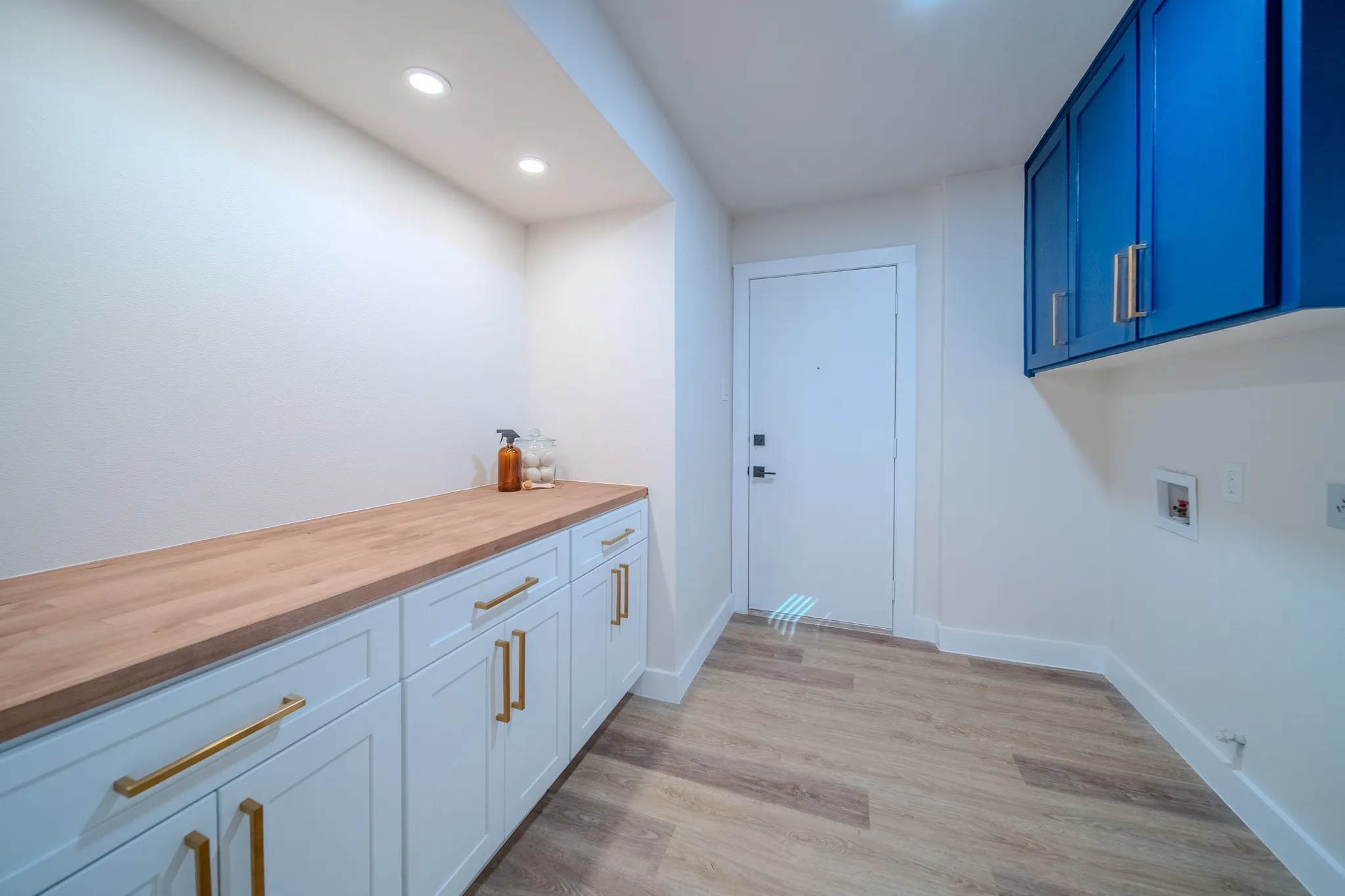 Laundry area with wood-finish flooring, recessed lighting, and a white door with black hardware