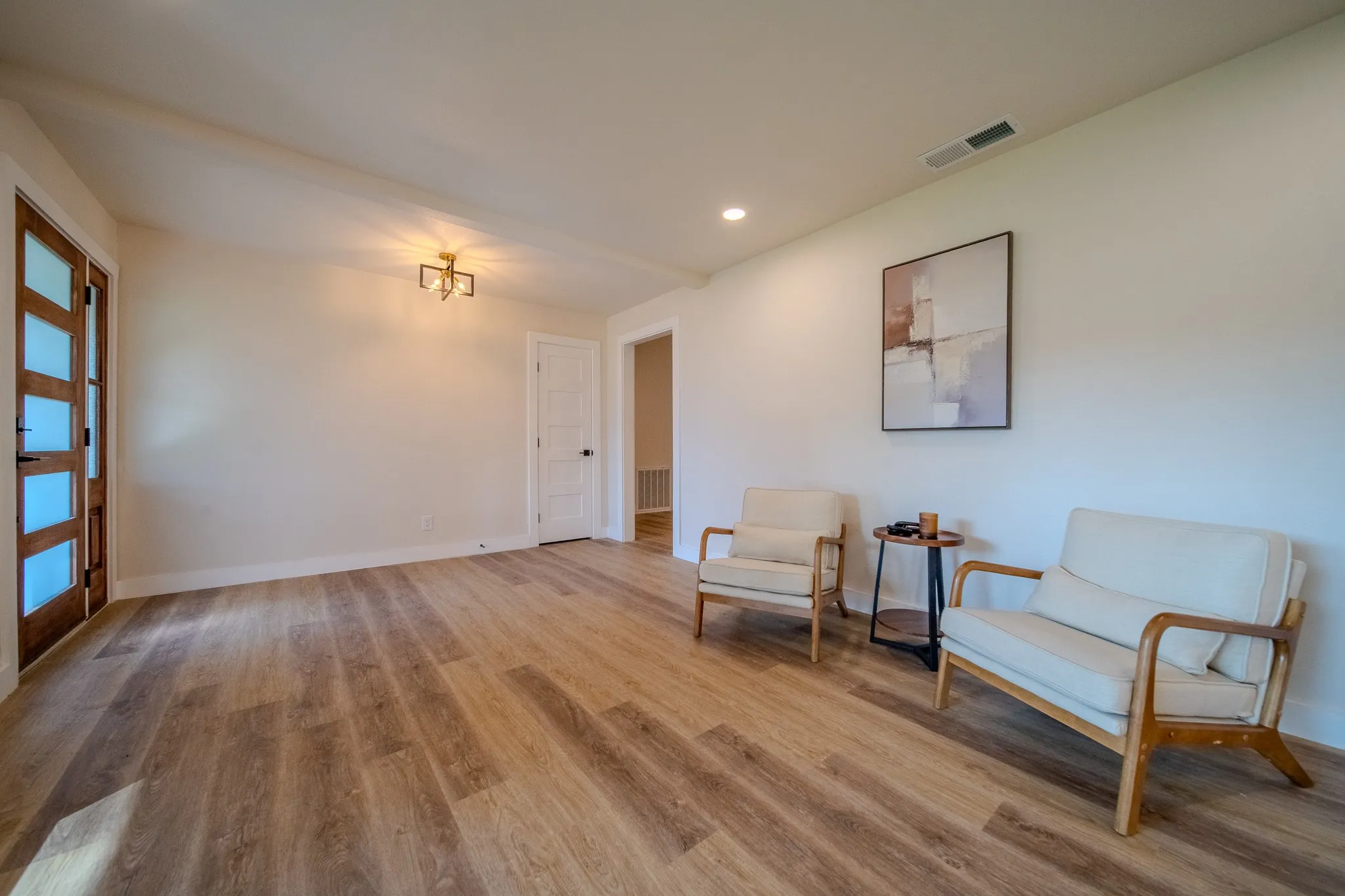 Wood-finish flooring, recessed lighting, and a modern ceiling fixture illuminate this open space