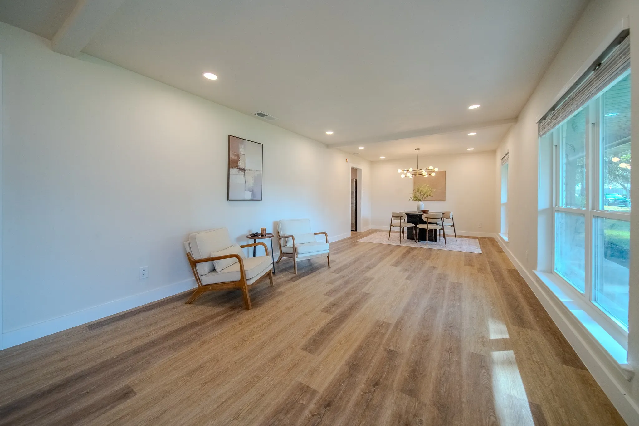 Recessed lighting illuminates the wood-finish flooring and white baseboards