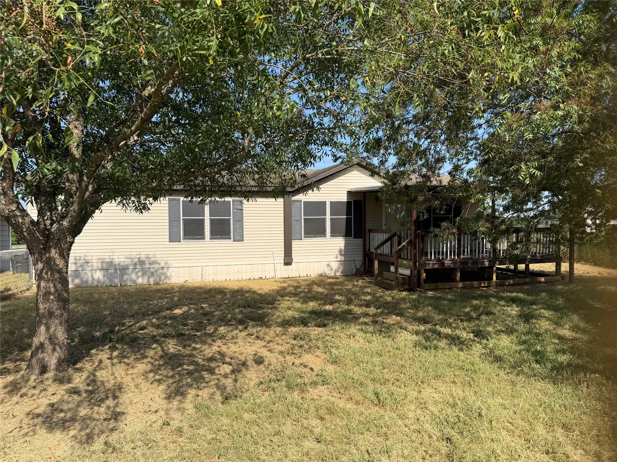 Large oak and pecan trees provide shade to the mobile home.