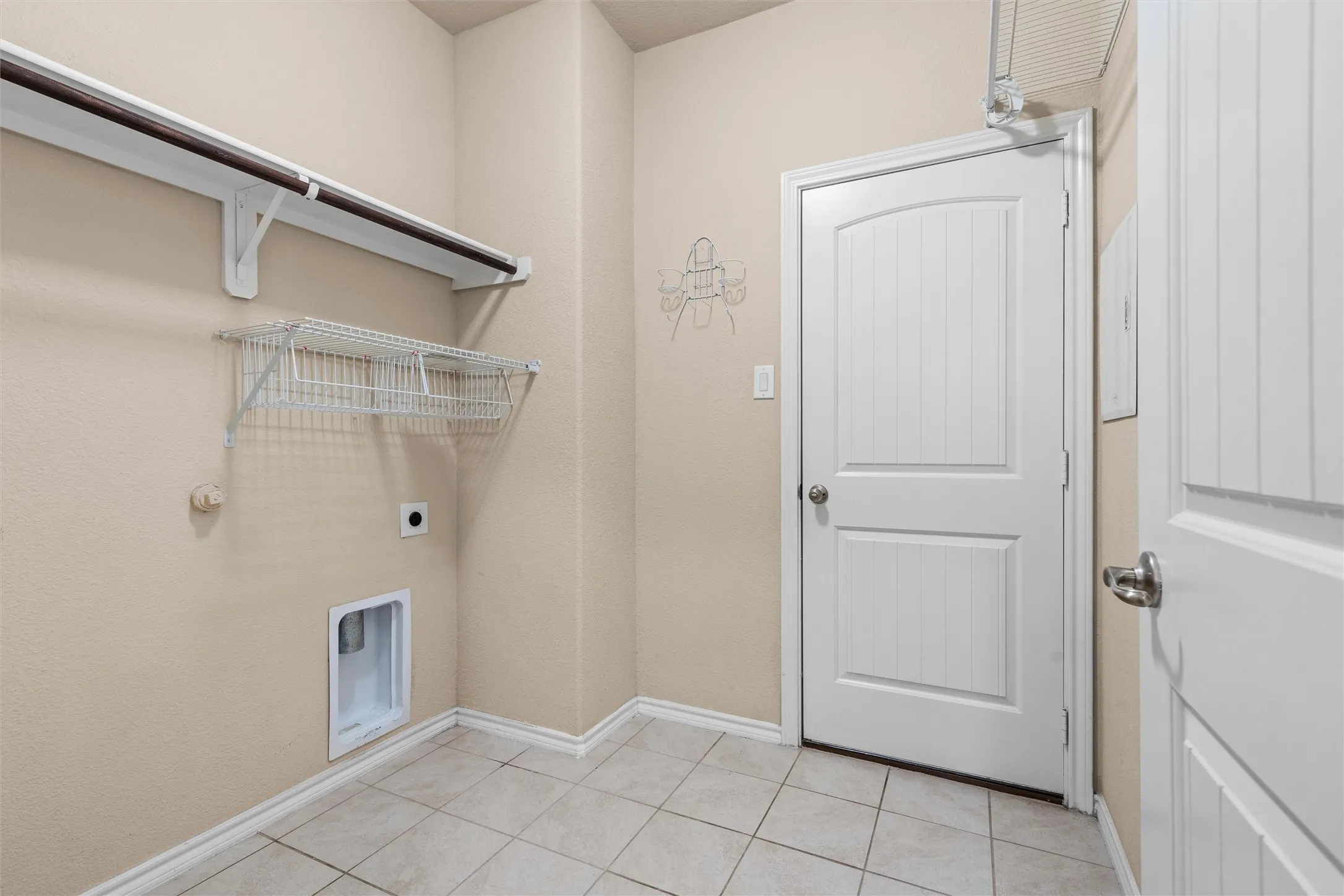 Laundry room featuring tile flooring, a hanging rod, and wire shelving