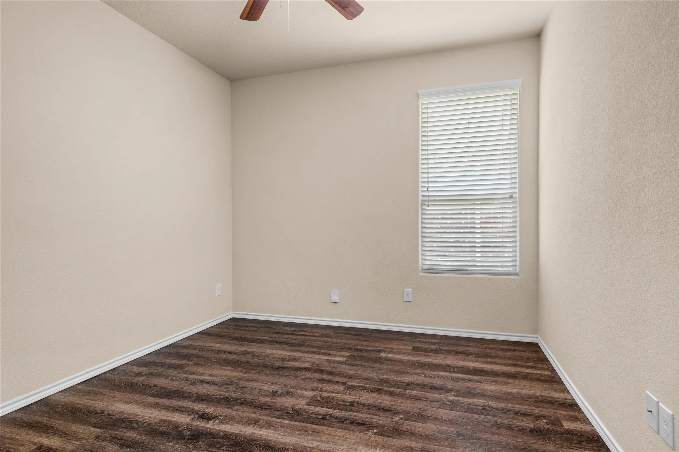 Third bedroom - Wood-finish flooring, neutral wall tones, window with horizontal blinds, and a ceiling fan with light fixture