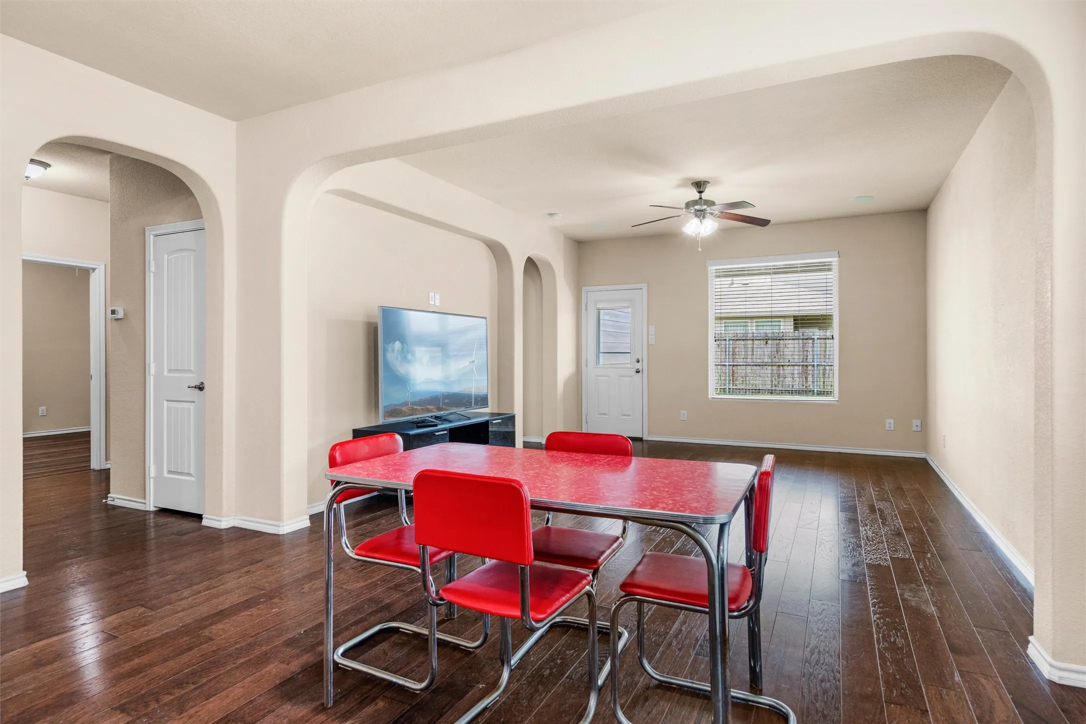 Open-concept dining livingspace with wood-finish flooring, arched doorways, and neutral-toned walls