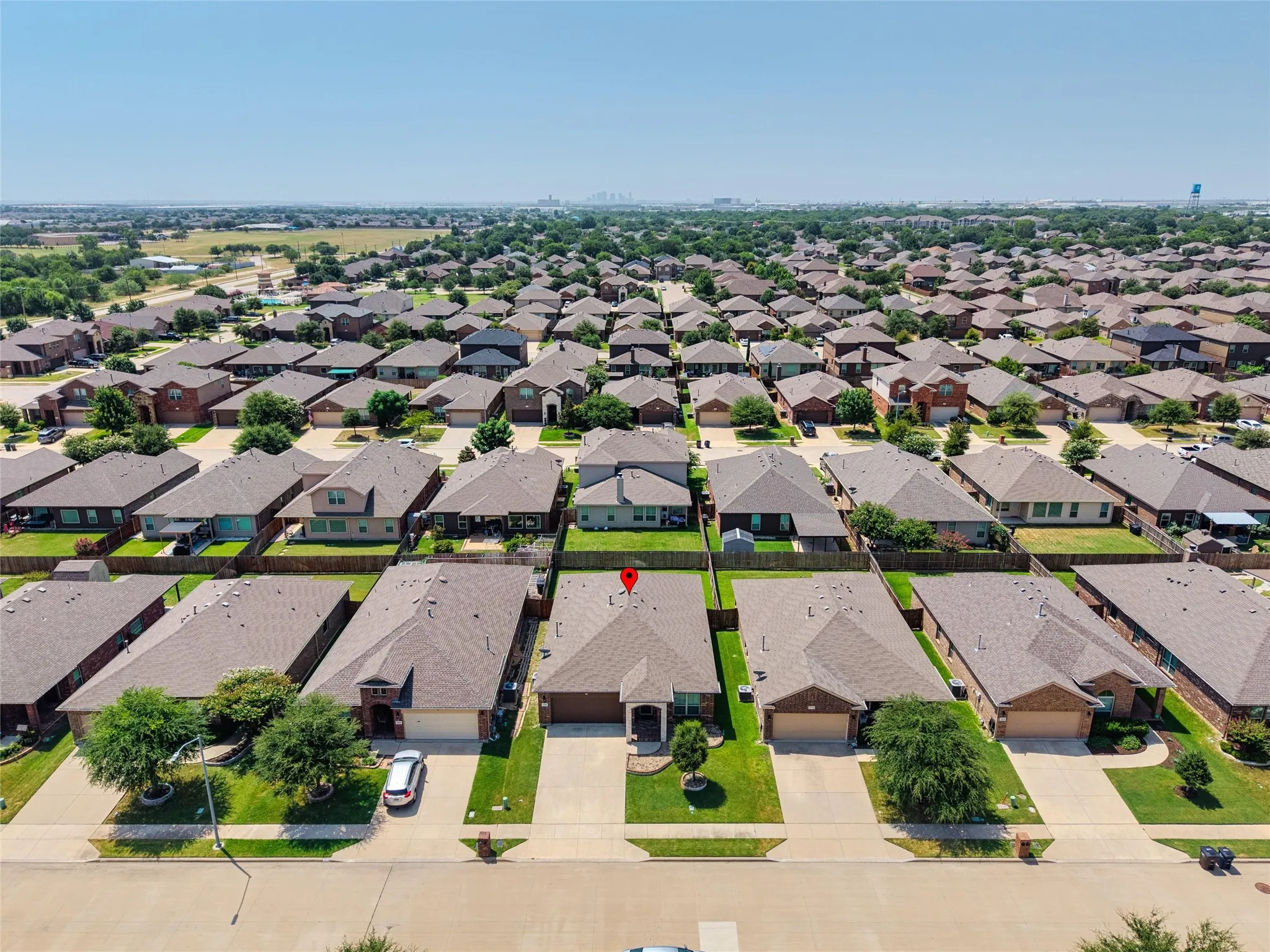 Aerial perspective highlighting the property with an attached two-car garage, concrete driveway, and established front landscaping
