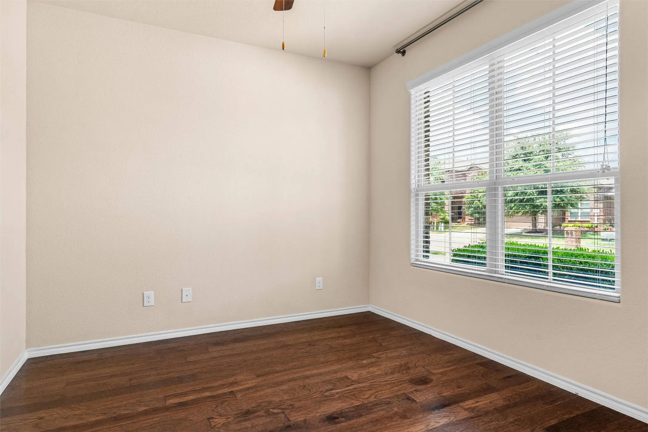 Front office / flex room Wood-finish flooring, neutral wall tones, and a window with horizontal blinds