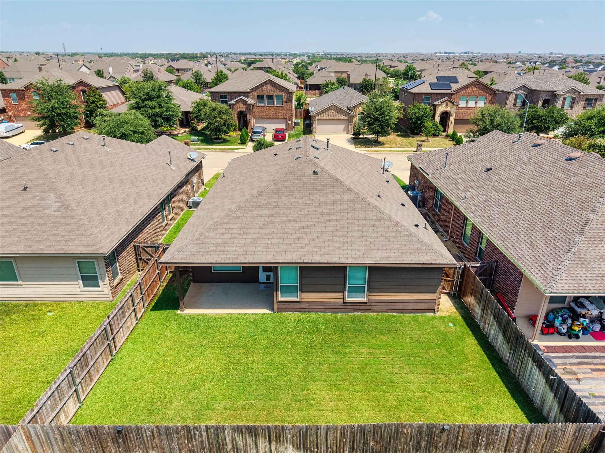 Expansive fenced backyard with a manicured lawn and concrete patio