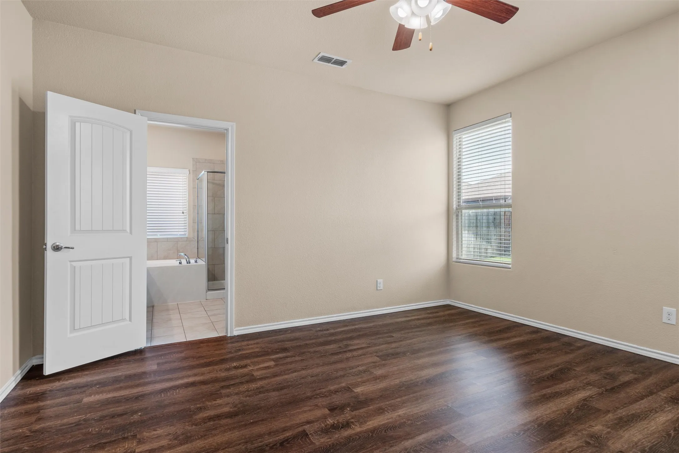Primary bedroom -Wood-finish flooring throughout, neutral wall tones, and a window with blinds