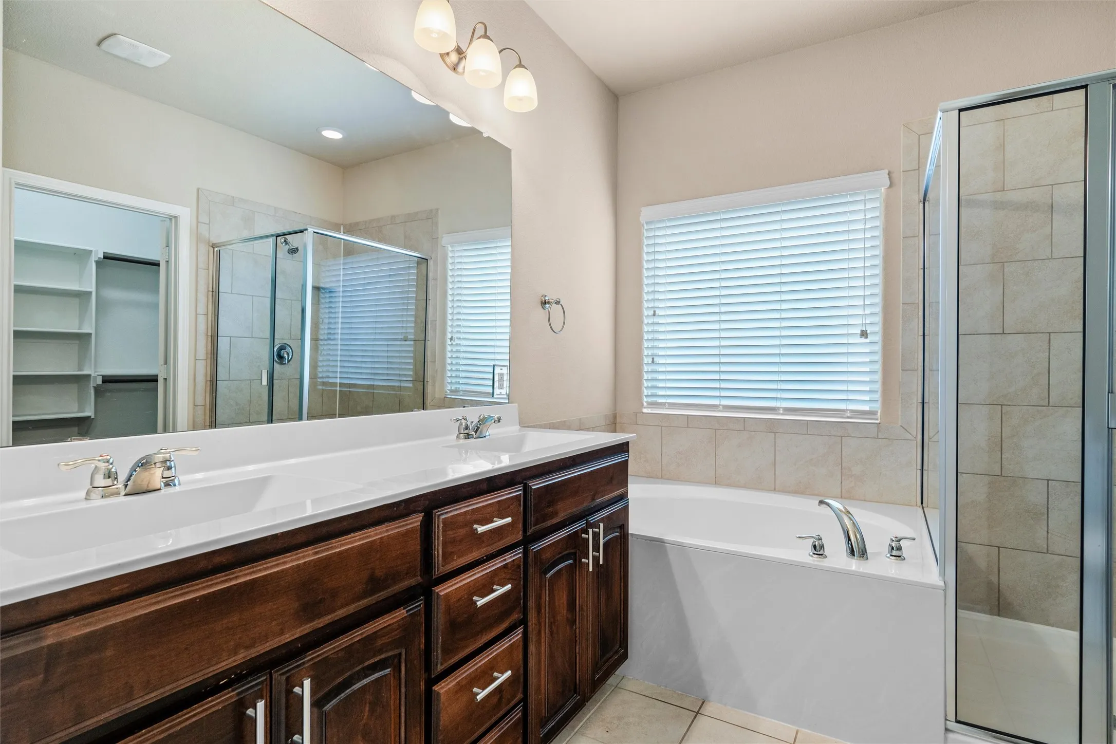 Primary ensuite - Double vanity with integrated sinks, dark wood-finish cabinetry, and polished chrome fixtures