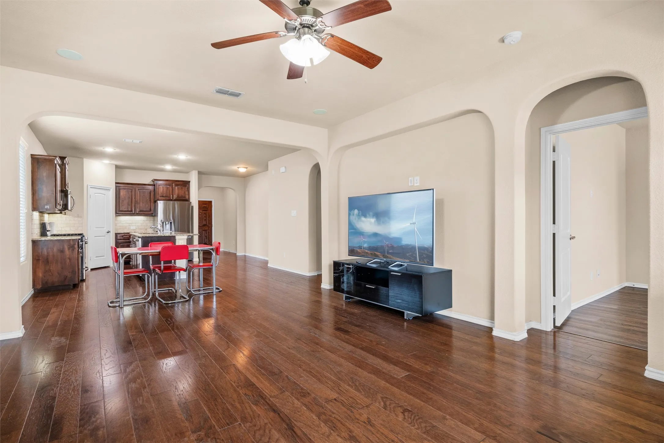 Open concept living space featuring wood-finish flooring, a ceiling fan, arched doorways, and recessed lighting