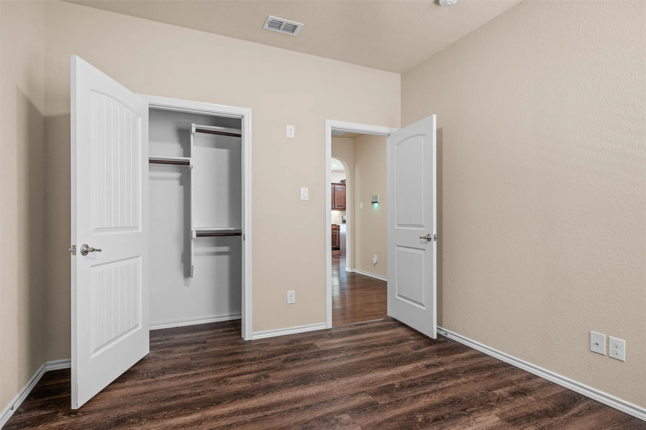Second bedroom - Wood-finish flooring, neutral-toned walls, and white trim