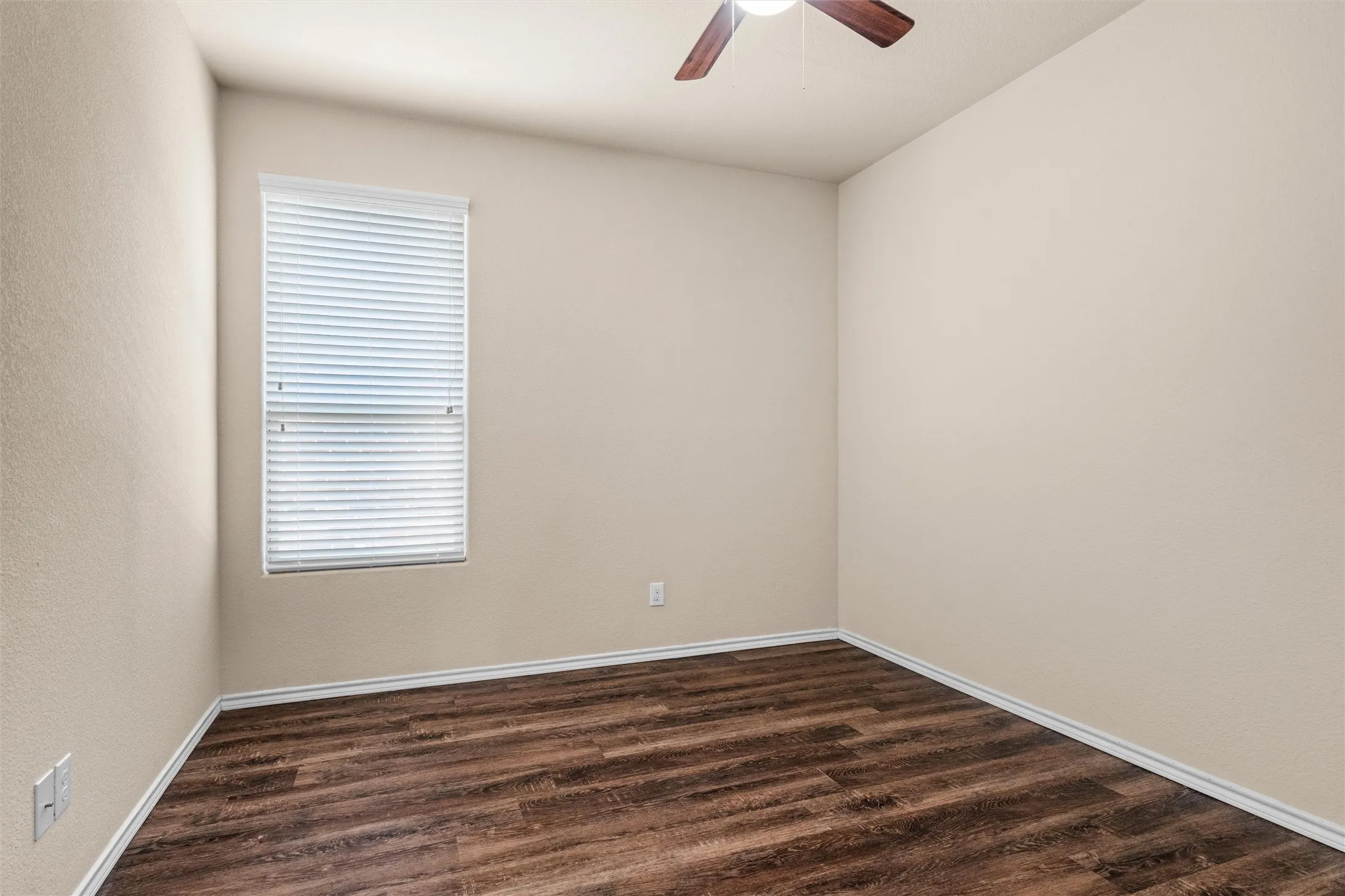 Second bedroom - Wood-finish flooring, neutral wall tones, window with horizontal blinds, and a ceiling fan with light fixture