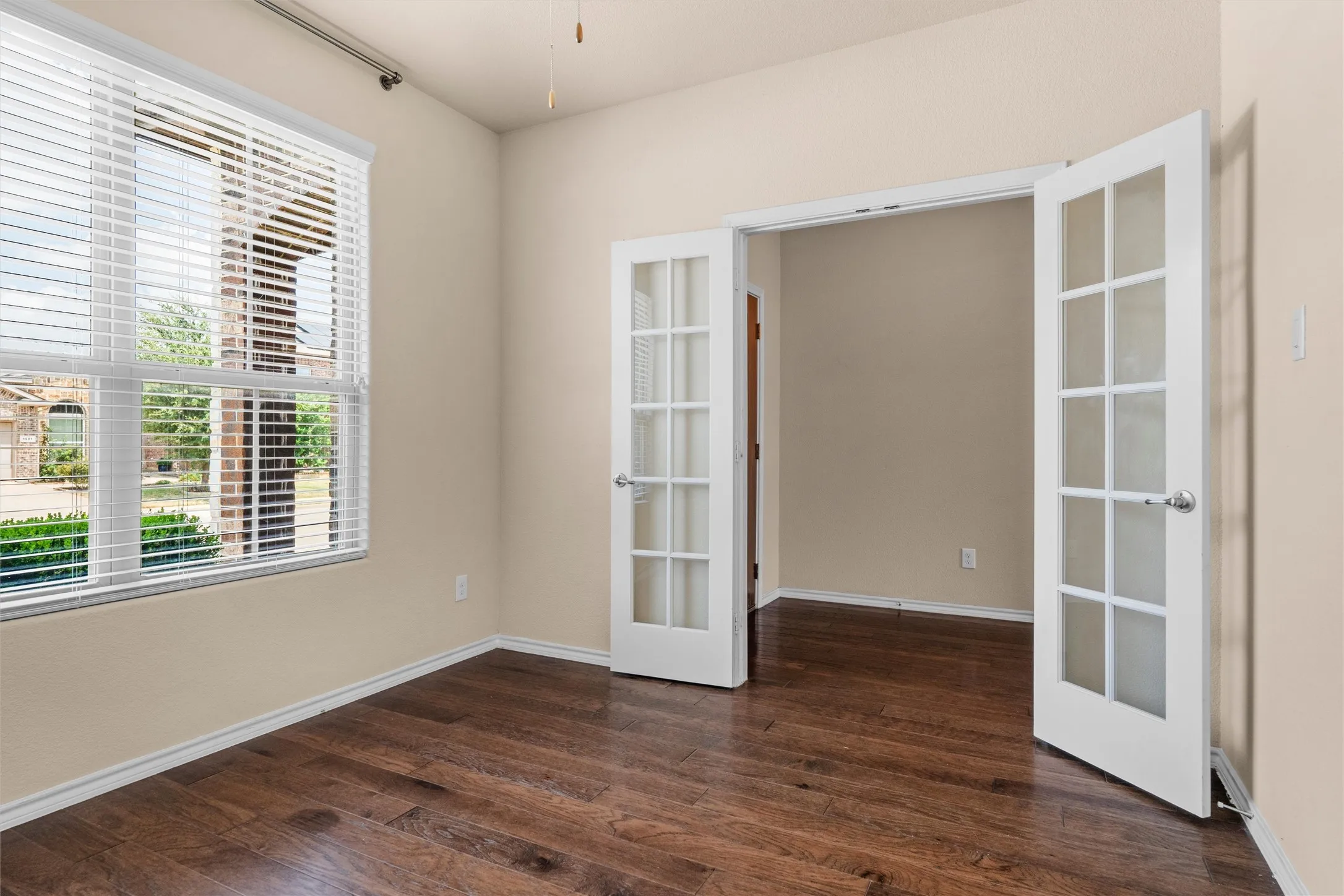 Front office / flex room Wood-finish flooring, neutral wall tones, and a window with horizontal blinds