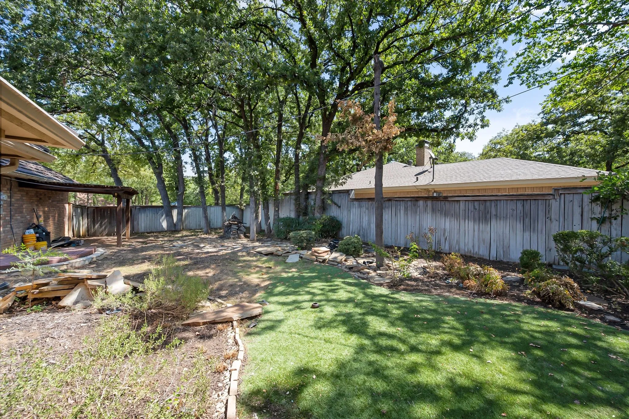 Expansive backyard with a manicured lawn, established landscaping, and mature trees providing natural shade