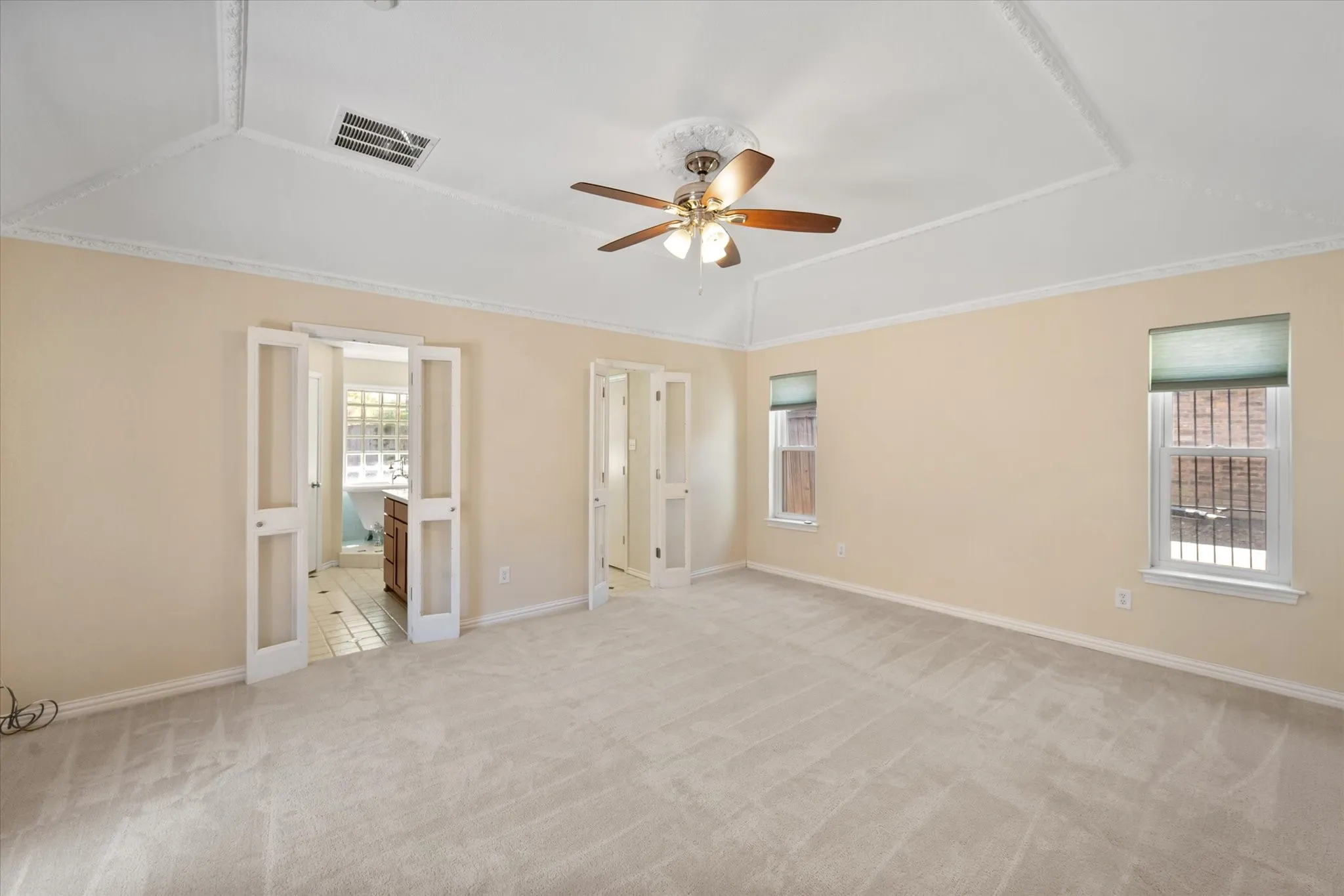Recessed ceiling with decorative trim, ceiling fan with light fixture, two windows, and two sets of double doors