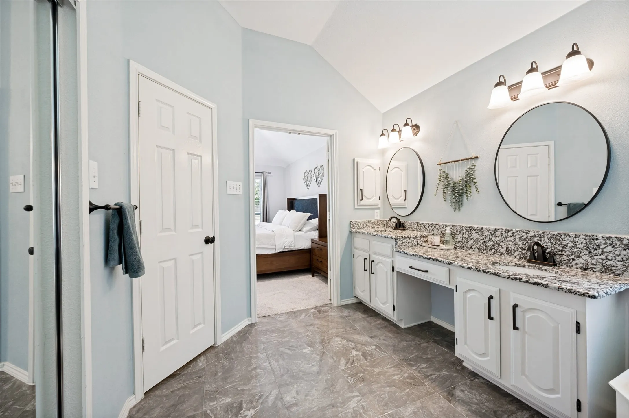 Dual vanity with stone countertops, integrated sinks, and individual round mirrors