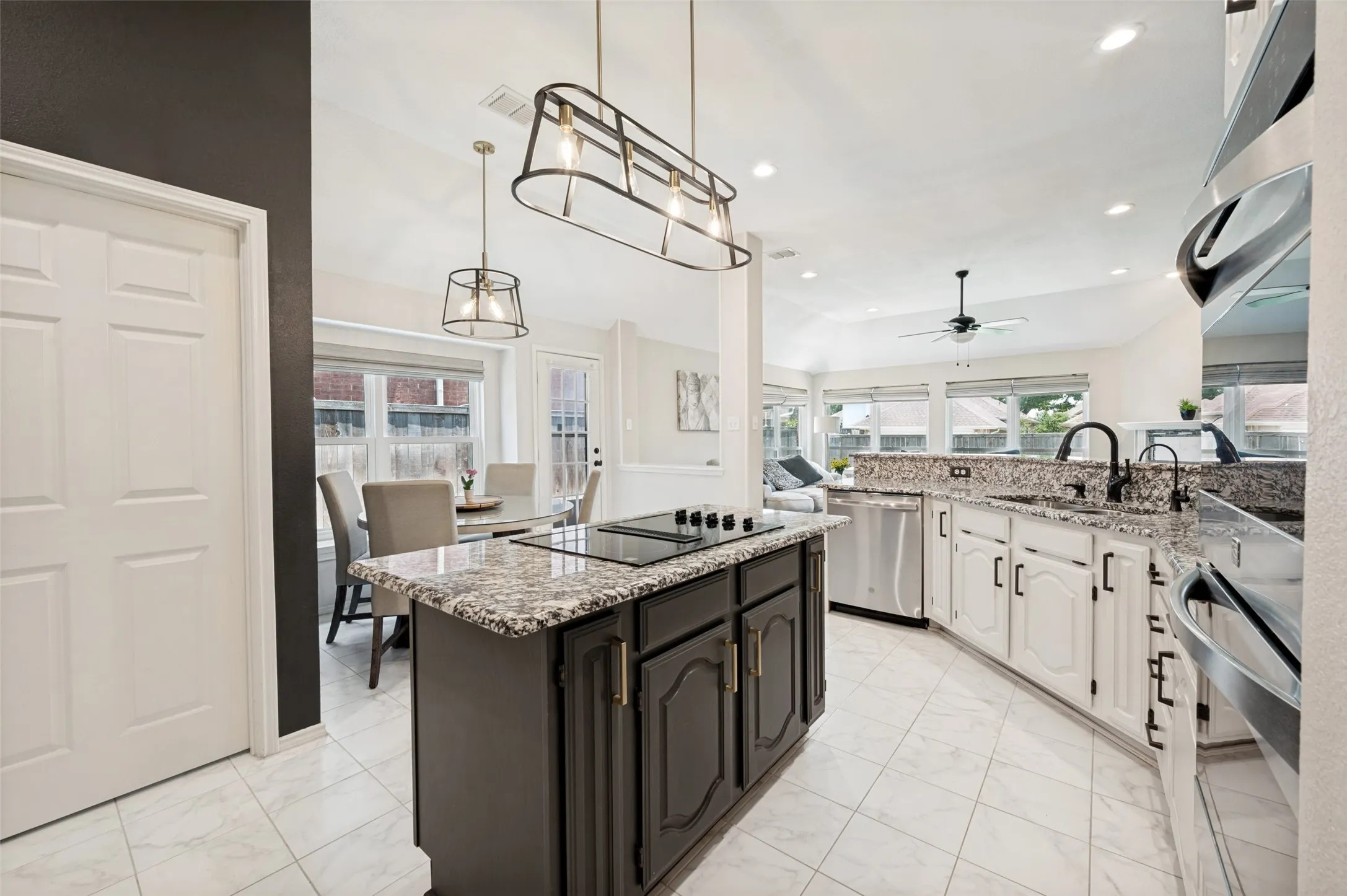 Kitchen featuring an island with built-in cooktop, granite countertops, tile flooring, and stainless steel appliances