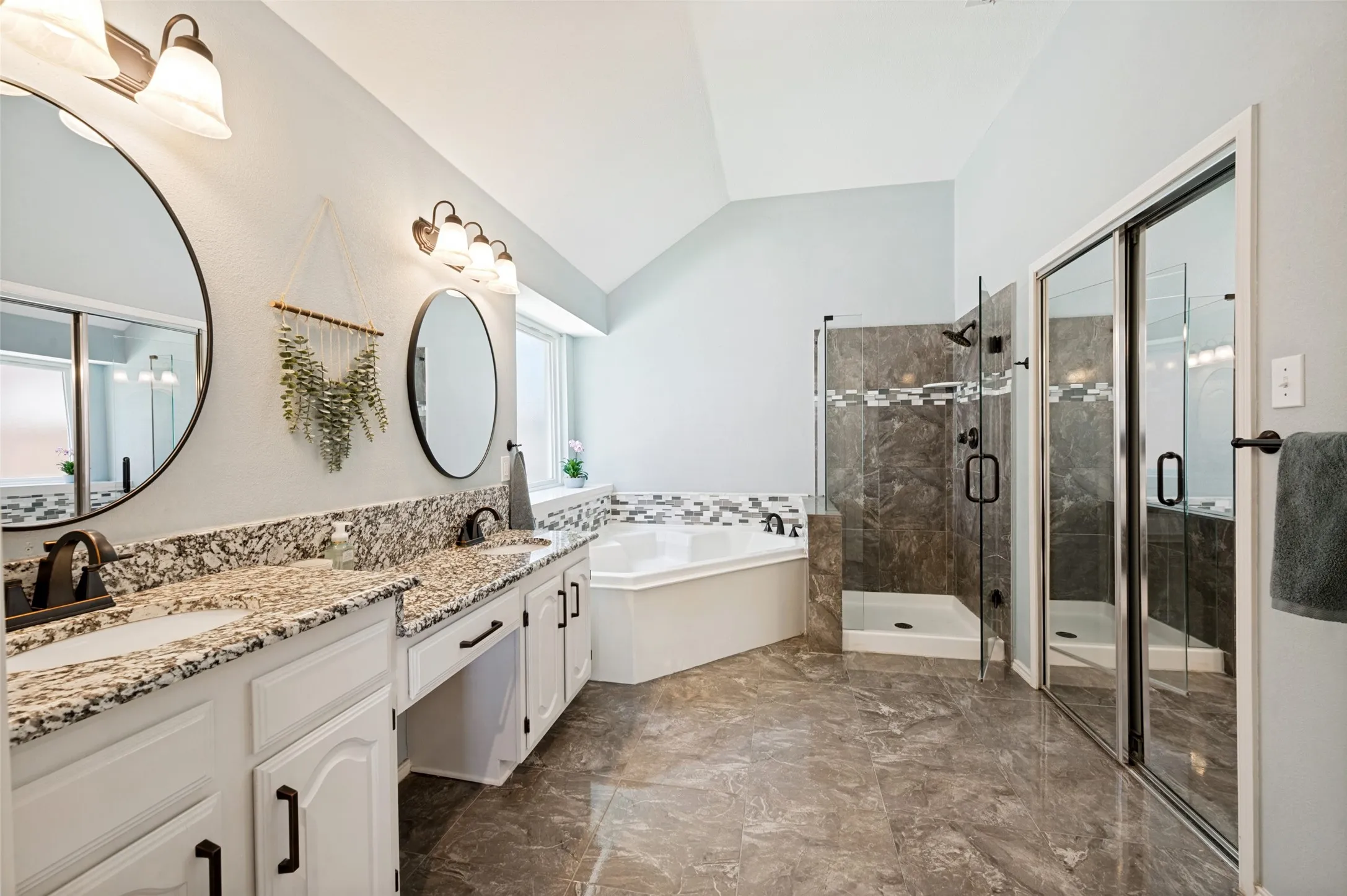 Dual vanity with granite countertops, a built-in corner tub, a glass-enclosed shower, and tile flooring