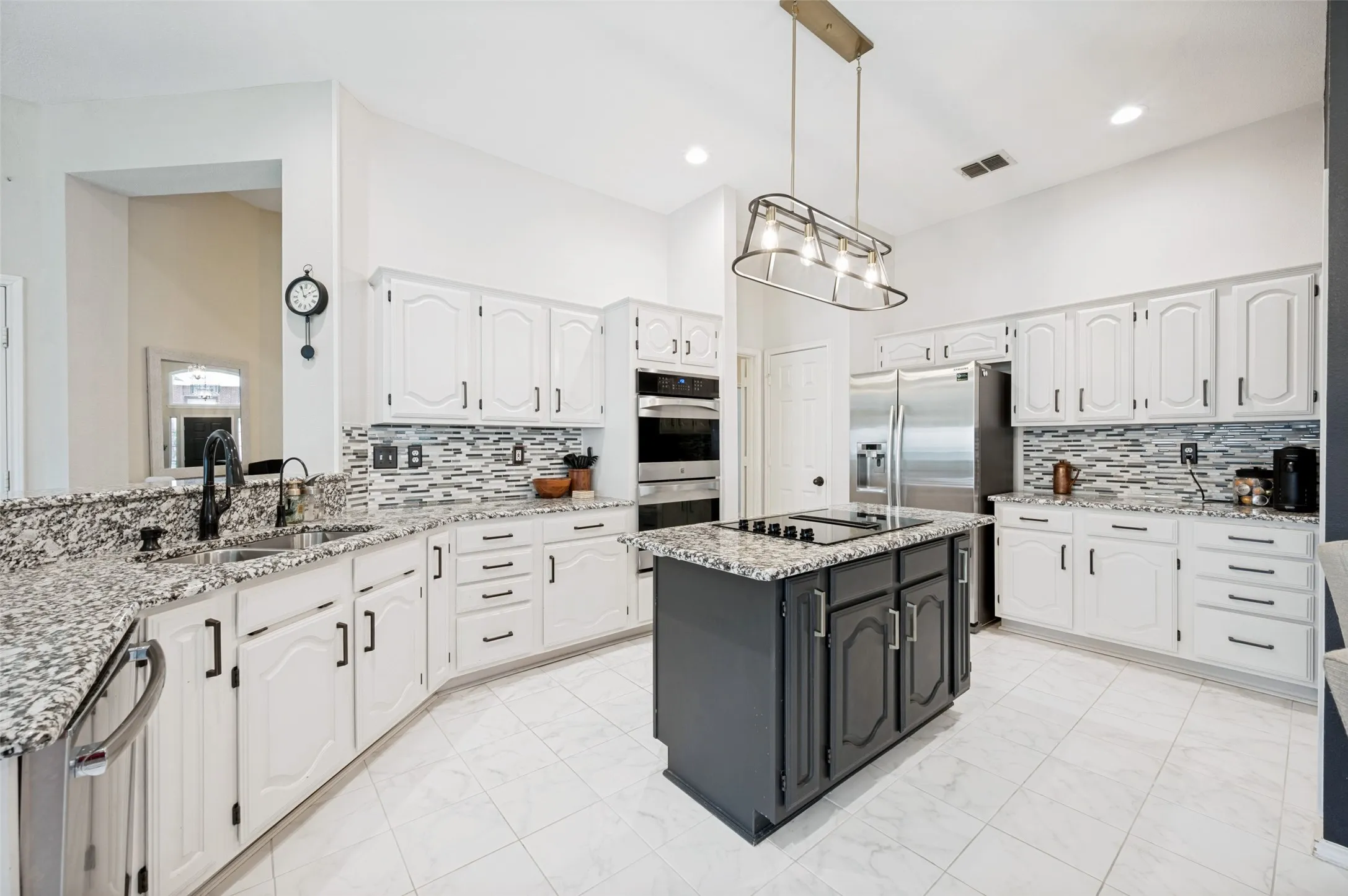 Kitchen featuring white cabinetry, speckled countertops, stainless steel appliances, a center island with cooktop, and tile flooring