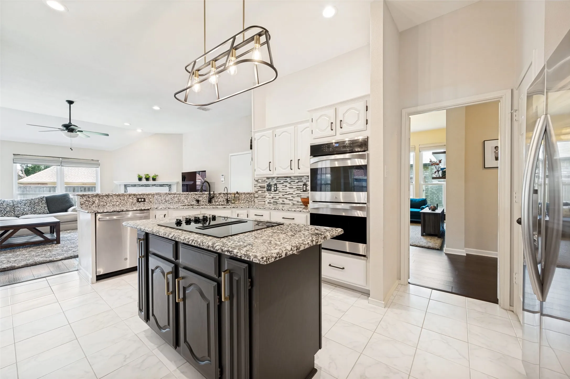 Kitchen featuring a center island with cooktop, white cabinetry, integrated stainless steel appliances, and tile flooring