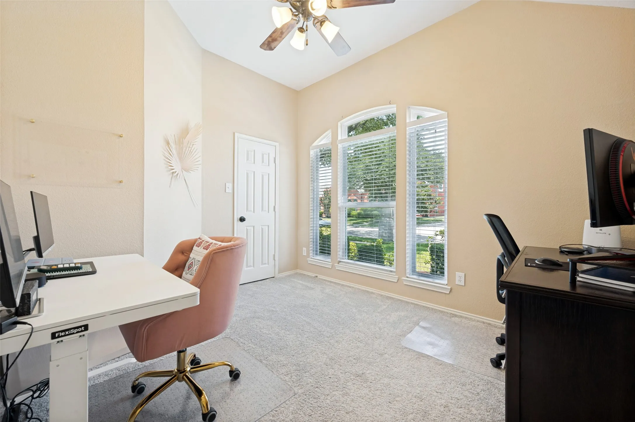 Vaulted ceiling with ceiling fan, arched windows, and light-colored carpeting