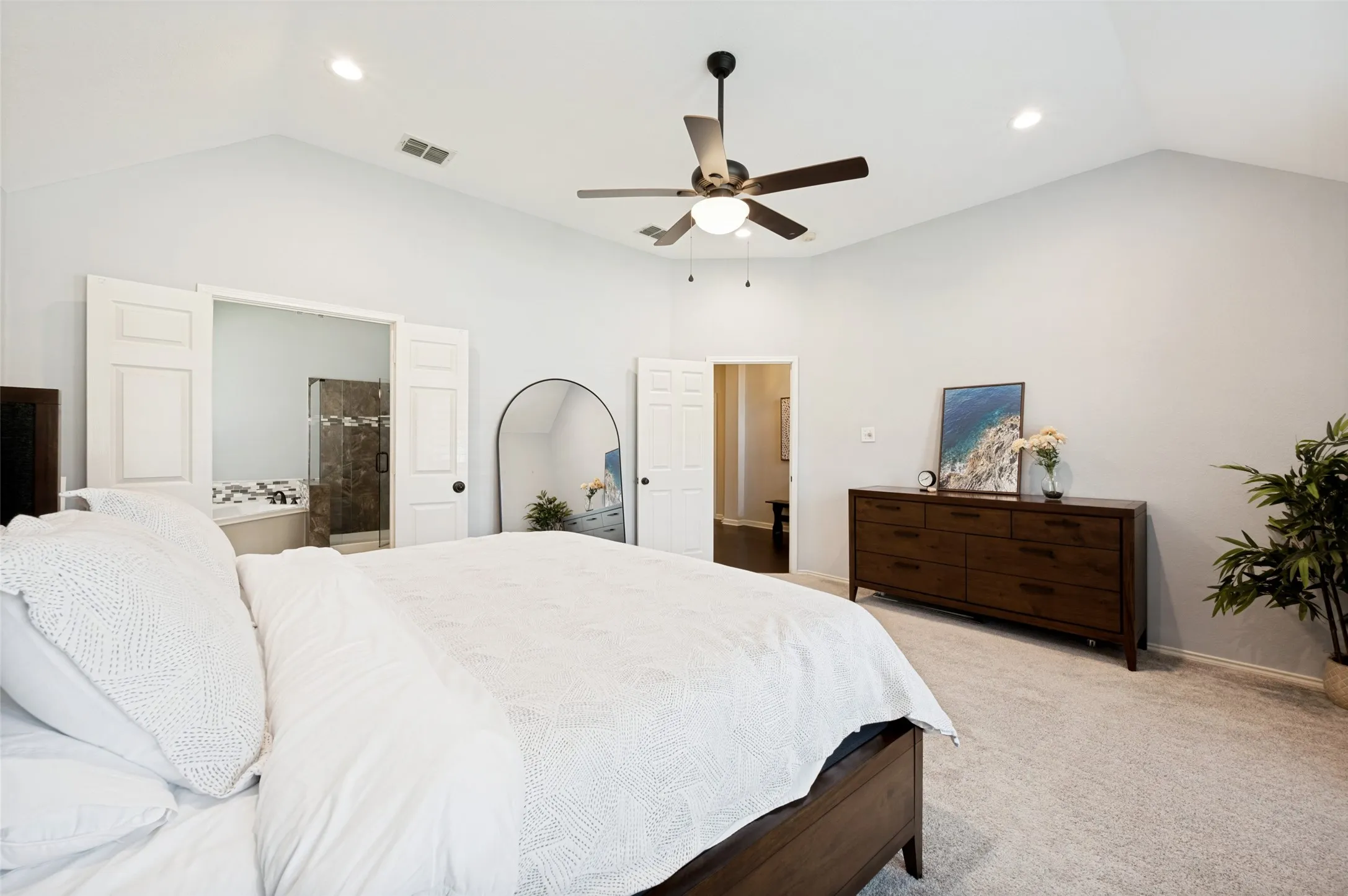 Vaulted ceiling, recessed lighting, ceiling fan with integrated light, carpet flooring, and a barn door entry to the adjacent room