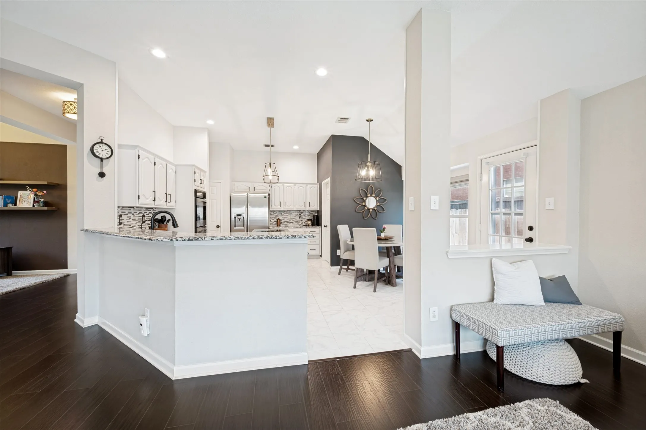 Hardwood-finish flooring, recessed lighting, white cabinetry, tile backsplash, and stainless steel appliances