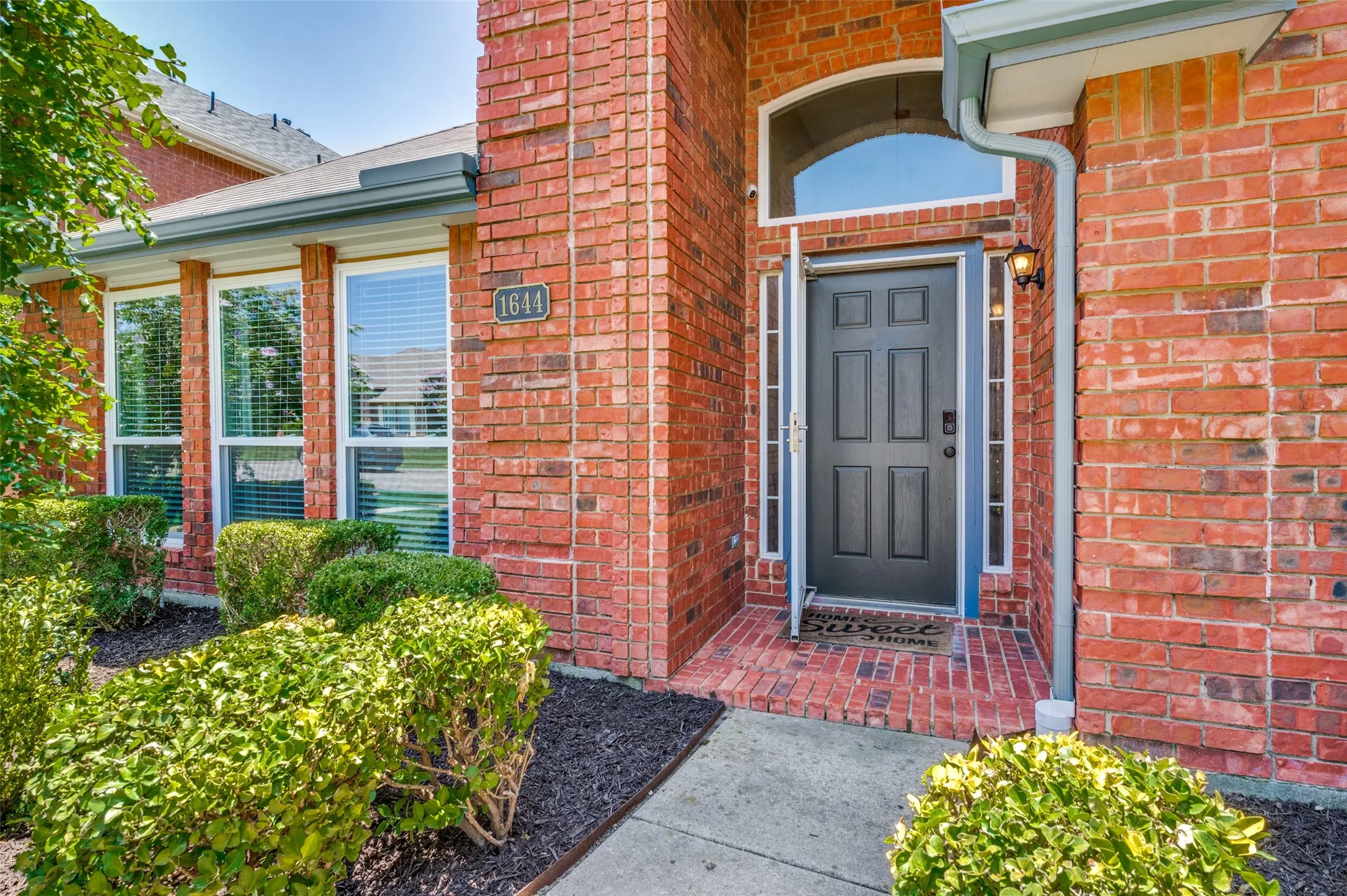 Red brick exterior featuring a panel-paneled entry door with sidelights and an arched transom