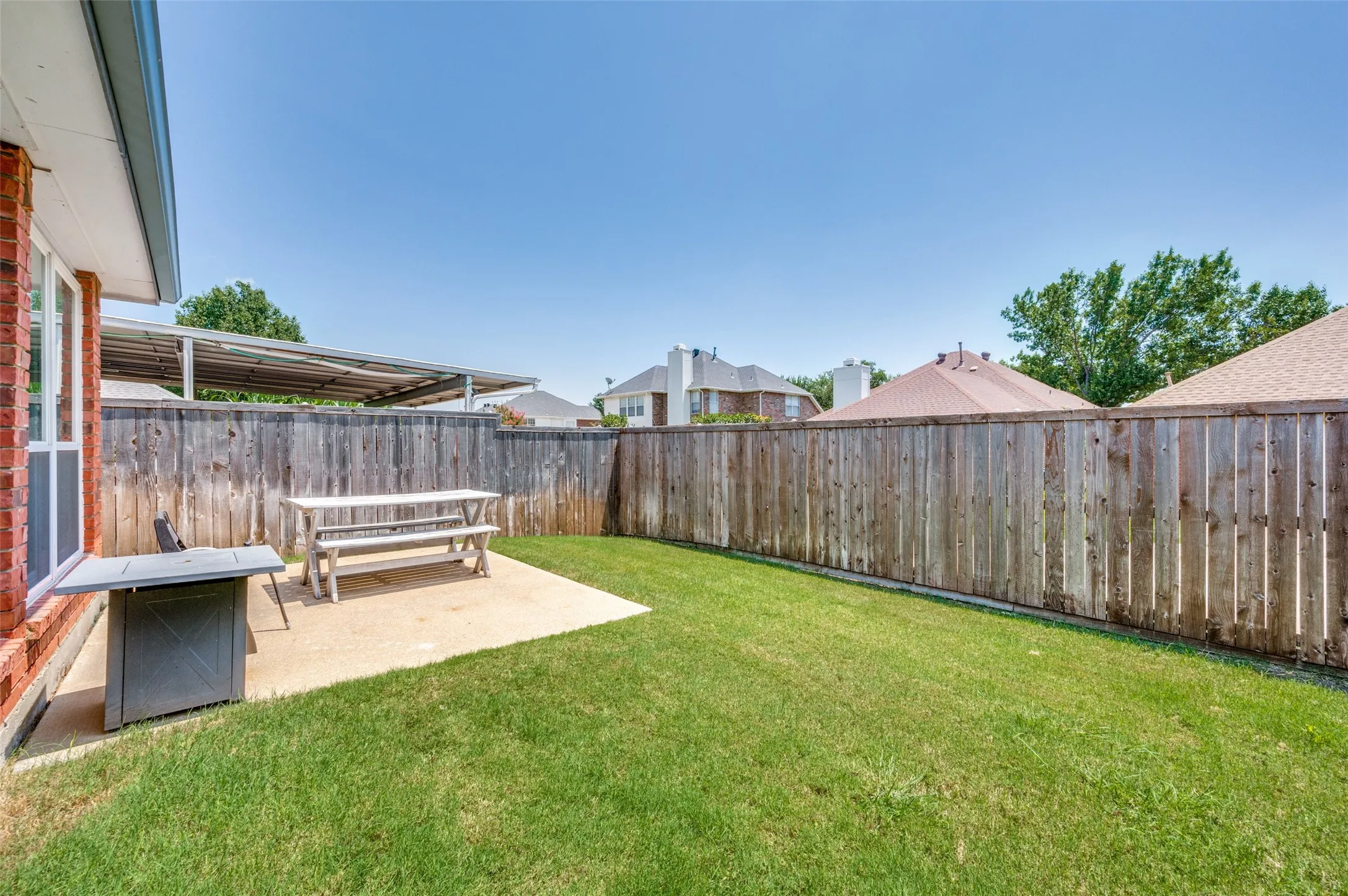 Expansive backyard with a manicured lawn, wood privacy fence, and concrete patio