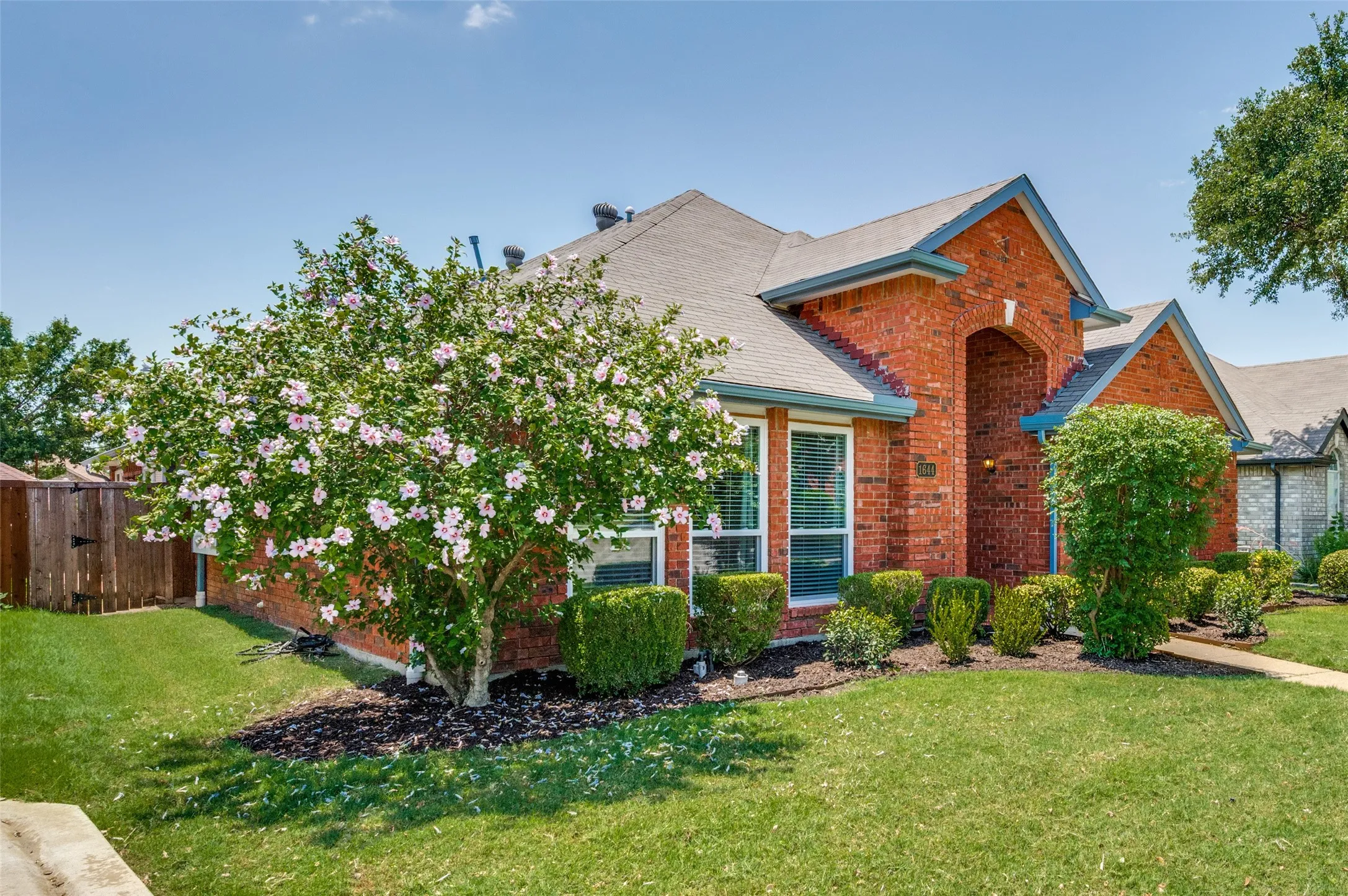 Brick exterior with a gray shingle roof, arched entryway, and multiple gables