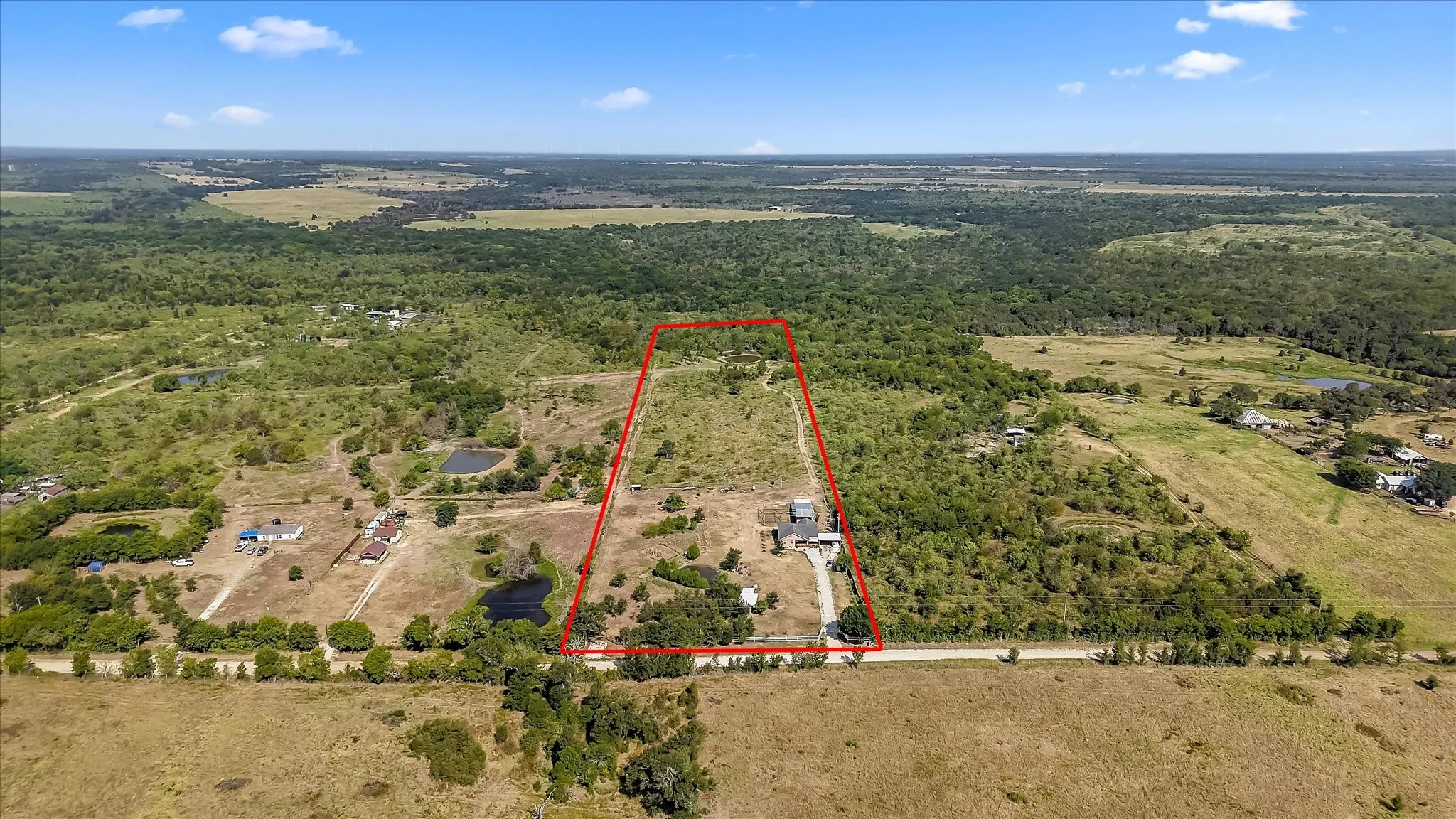 Expansive acreage featuring a perimeter outline, a winding roadway, and a mix of open fields and densely wooded areas