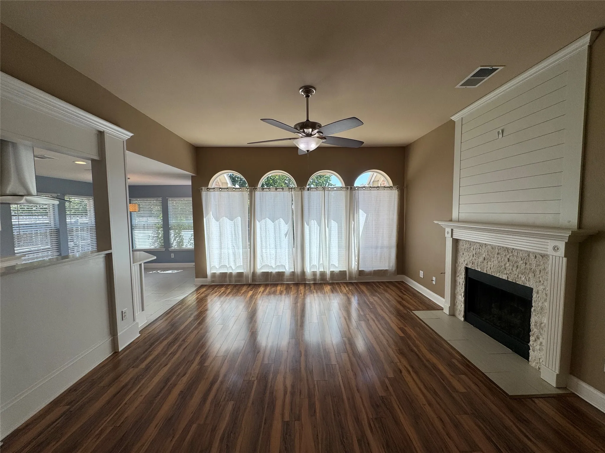 Wood-finish flooring throughout, featuring a fireplace with a stone surround and decorative mantel