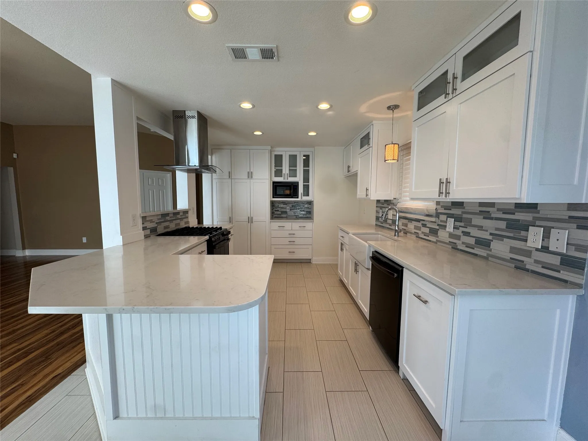 Kitchen featuring white cabinetry, light countertops, stainless steel range hood, and tile backsplash