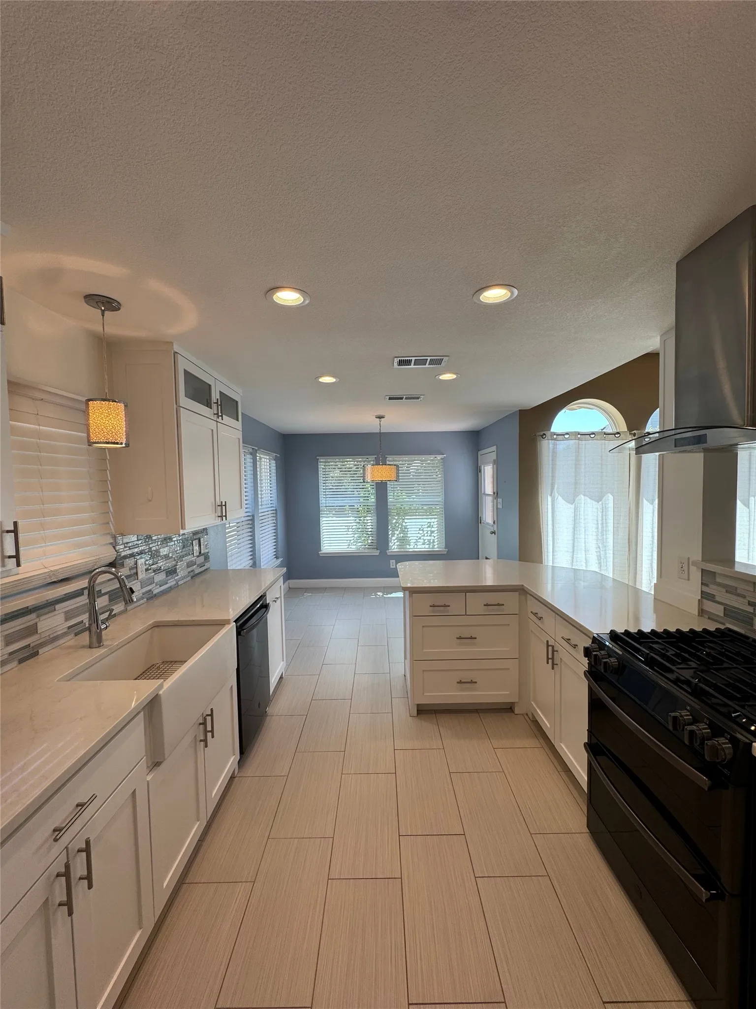 Kitchen featuring white cabinetry, light-toned countertops, a farm sink, and a tile backsplash