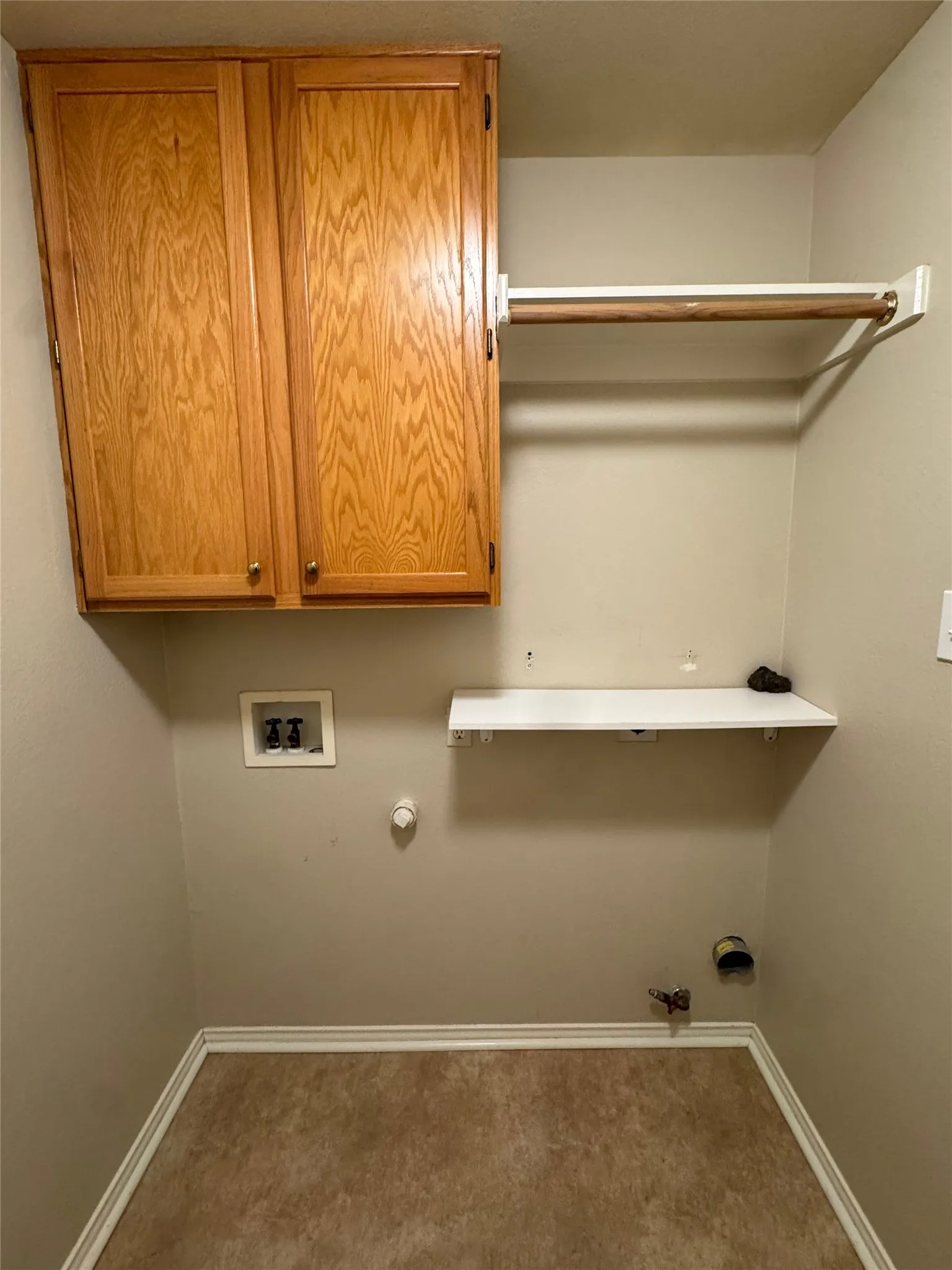 Wood-finish wall cabinetry, integrated clothing rod, wall-mounted shelving, and wood-finish flooring