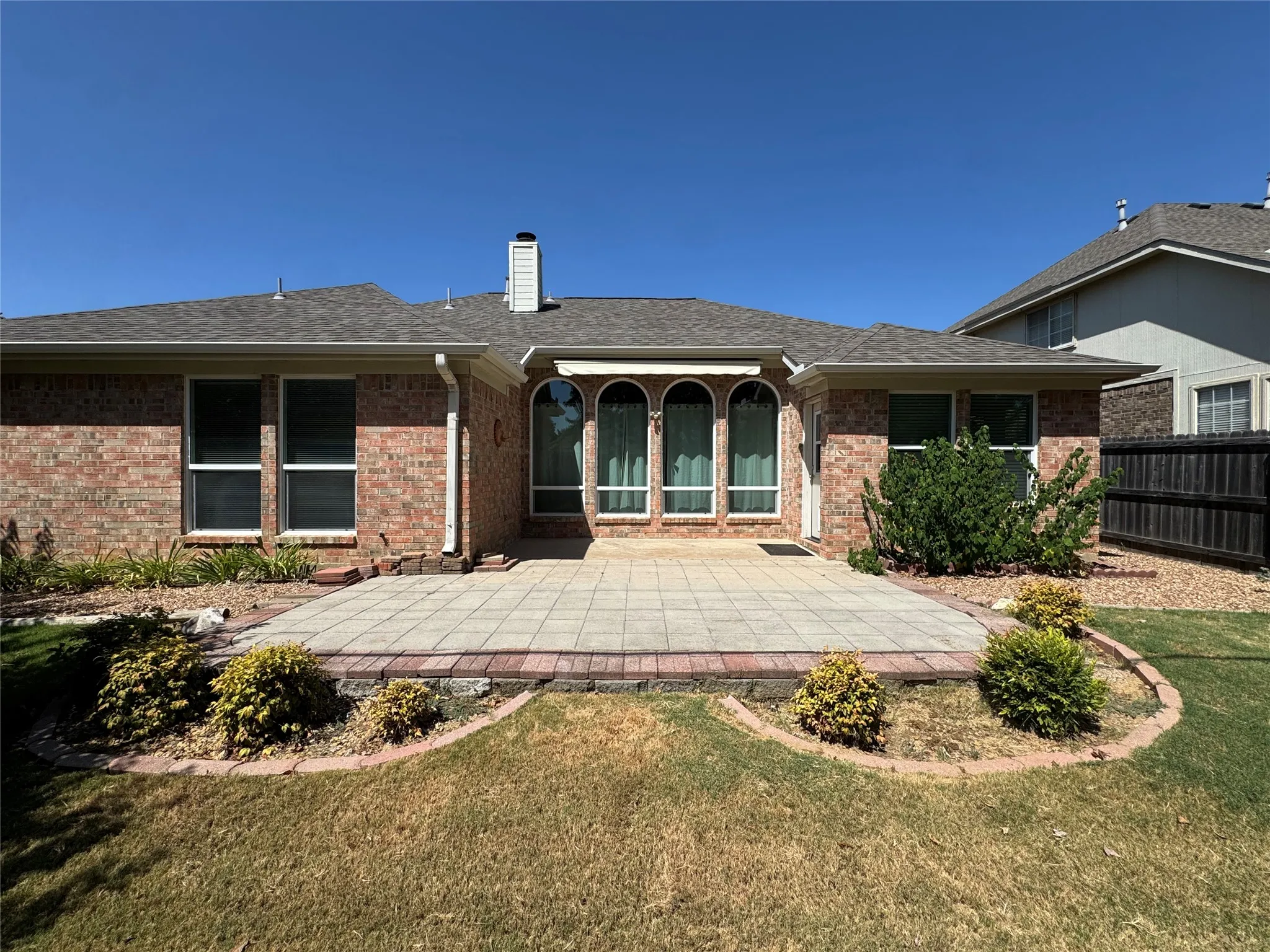 Brick exterior featuring a patio with paver stones and decorative landscaping