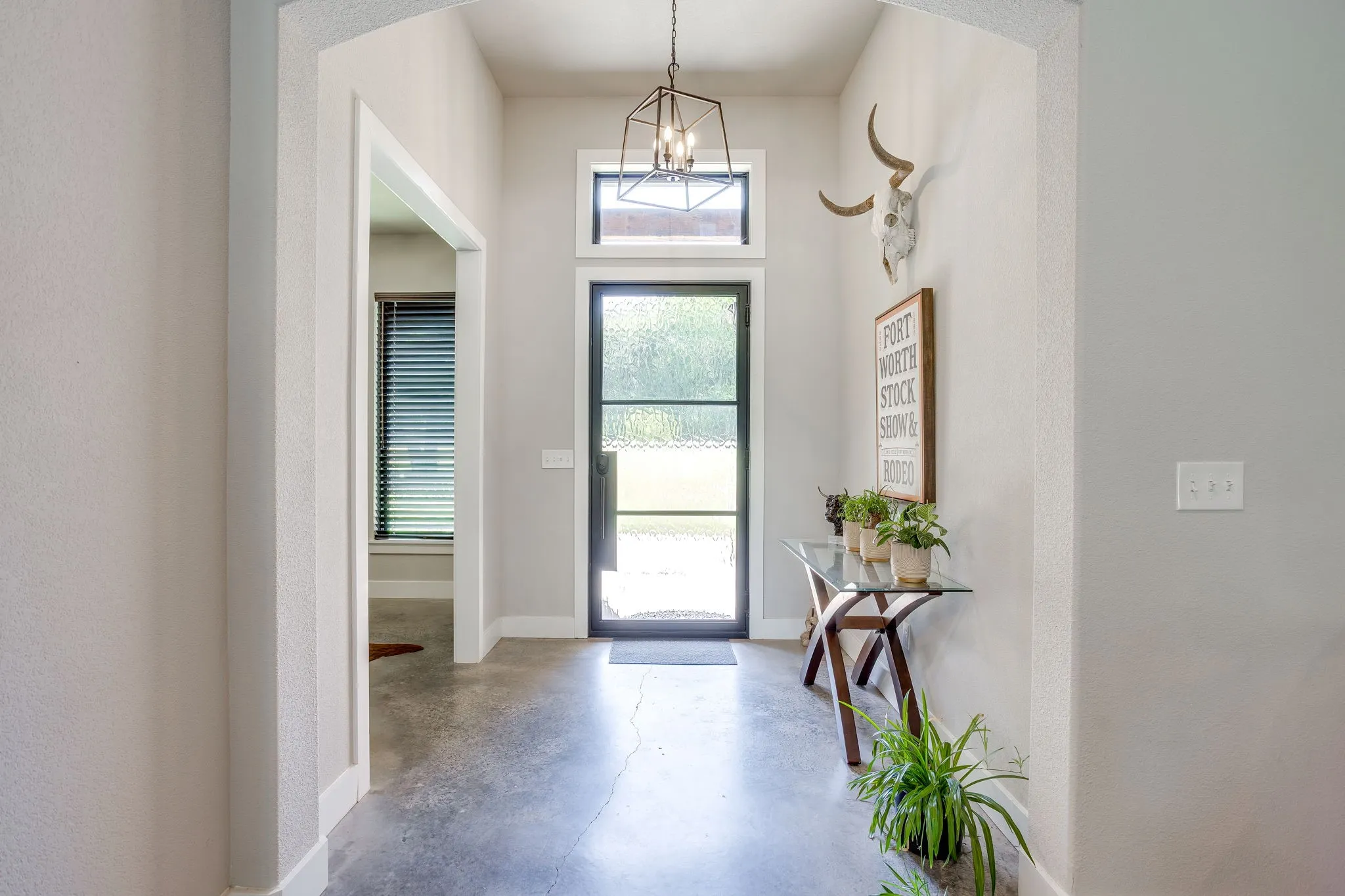Entryway featuring a full-light door with transom window, concrete flooring, and an arched doorway