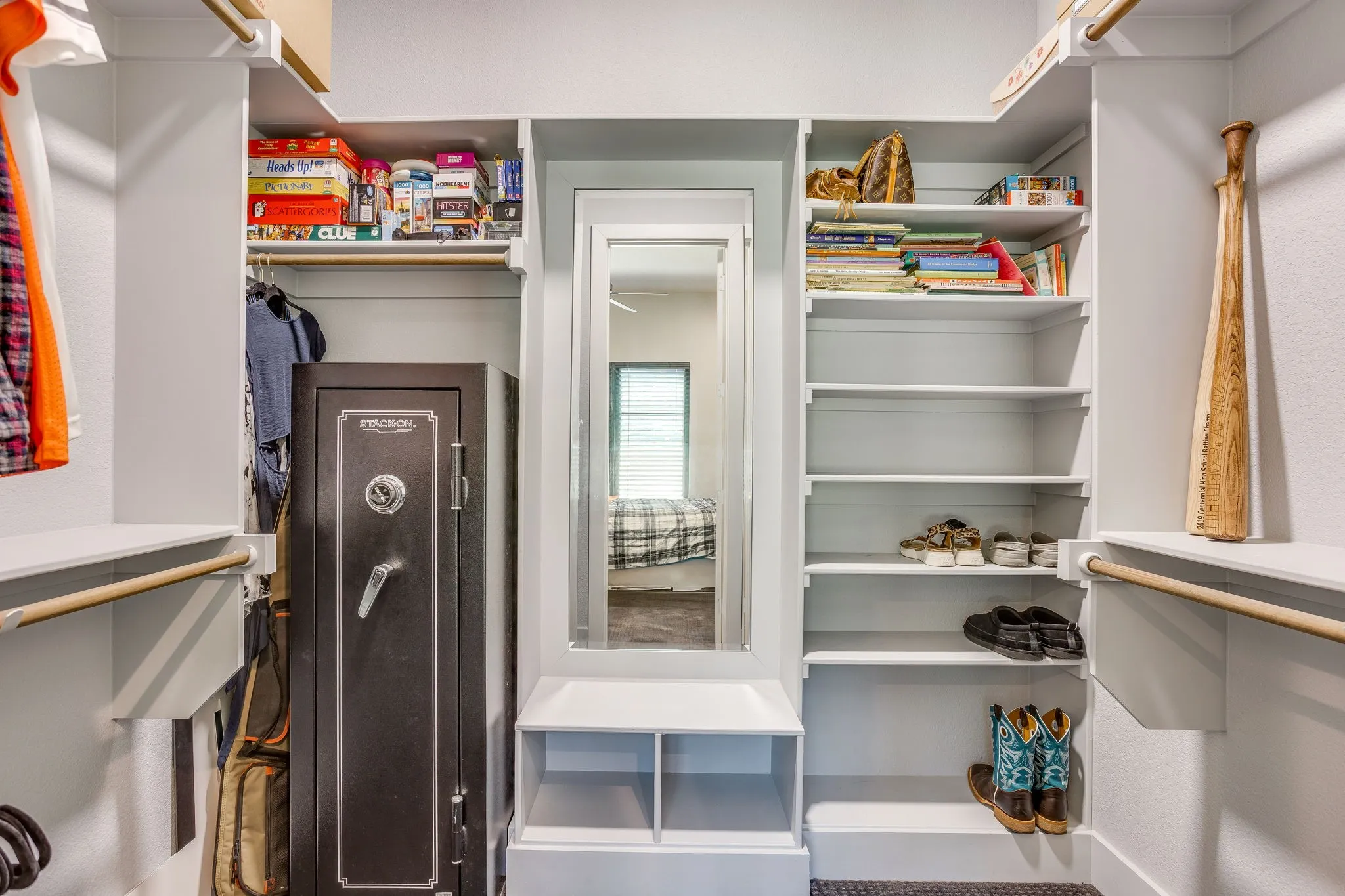 Built-in closet system featuring multiple shelving units, hanging rods, and a full-length mirror