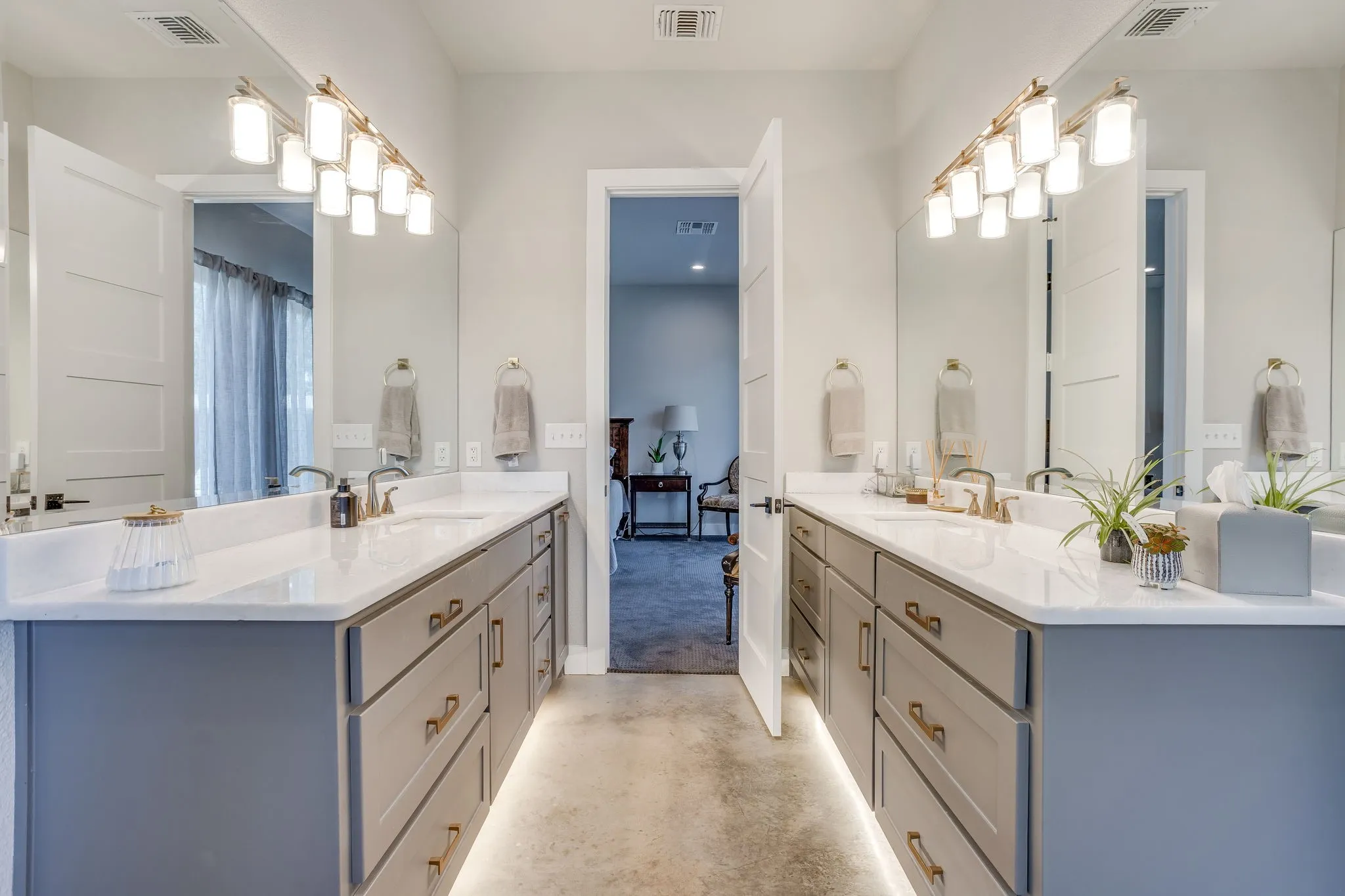 Dual vanities with undermount sinks, white countertops, and integrated lighting