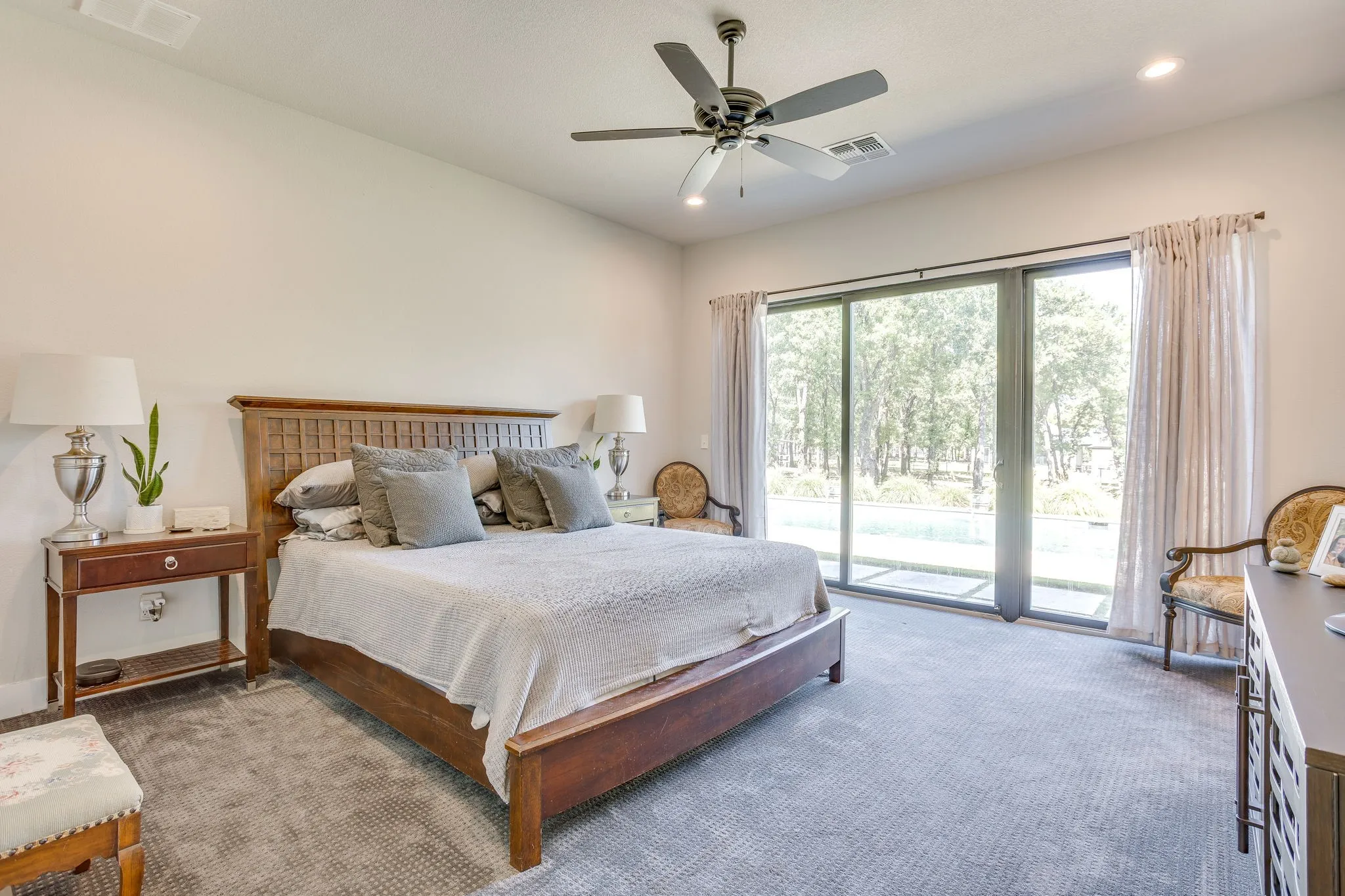 Sliding glass doors, recessed lighting, ceiling fan, textured carpeting, and light-colored wall finishes
