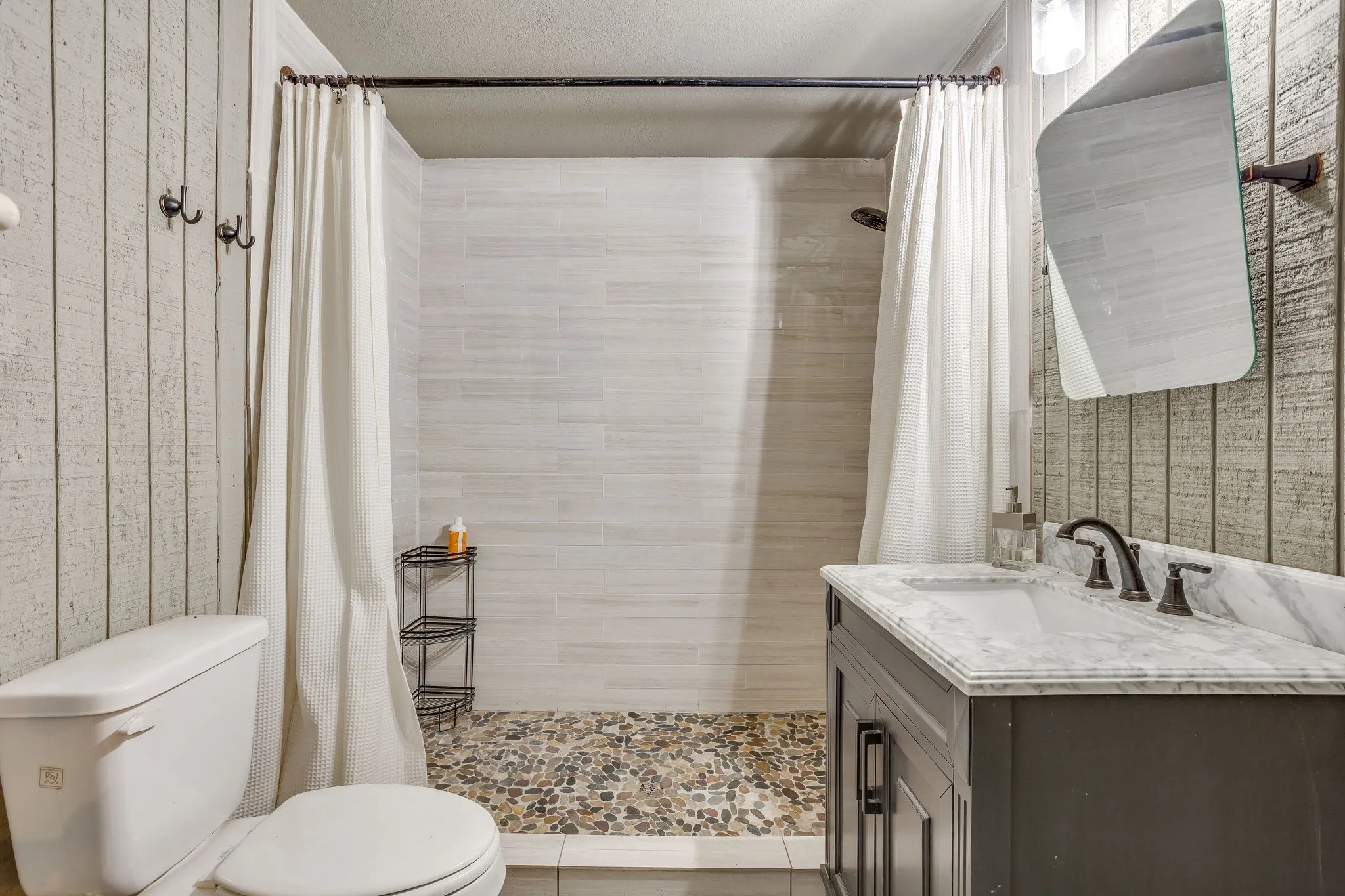 Pool house bathroom featuring walk-in shower with pebble tile flooring and horizontal tile surround