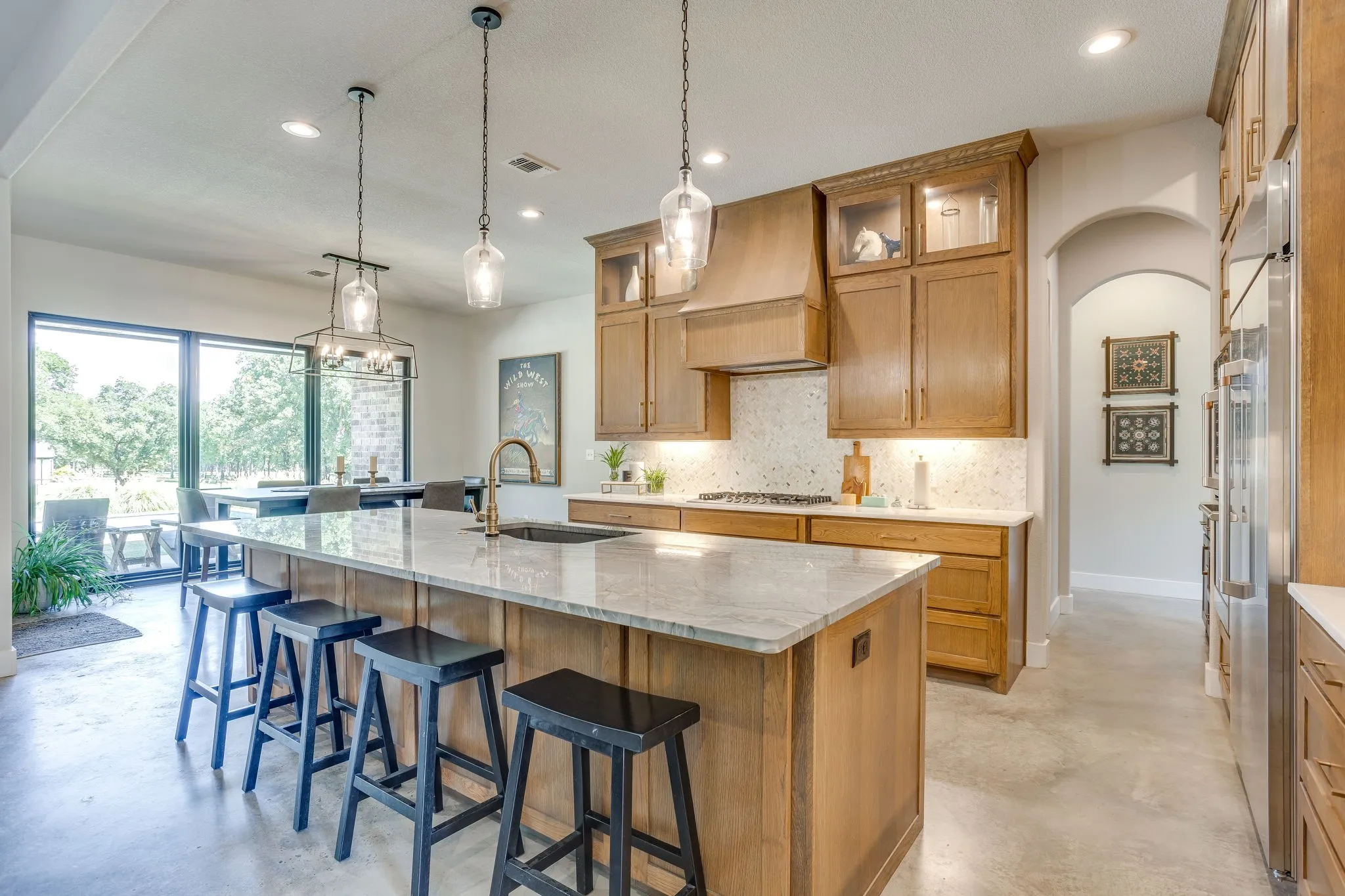 Spacious kitchen featuring an expansive island with a stone countertop, wood cabinetry, a tiled backsplash, and recessed lighting