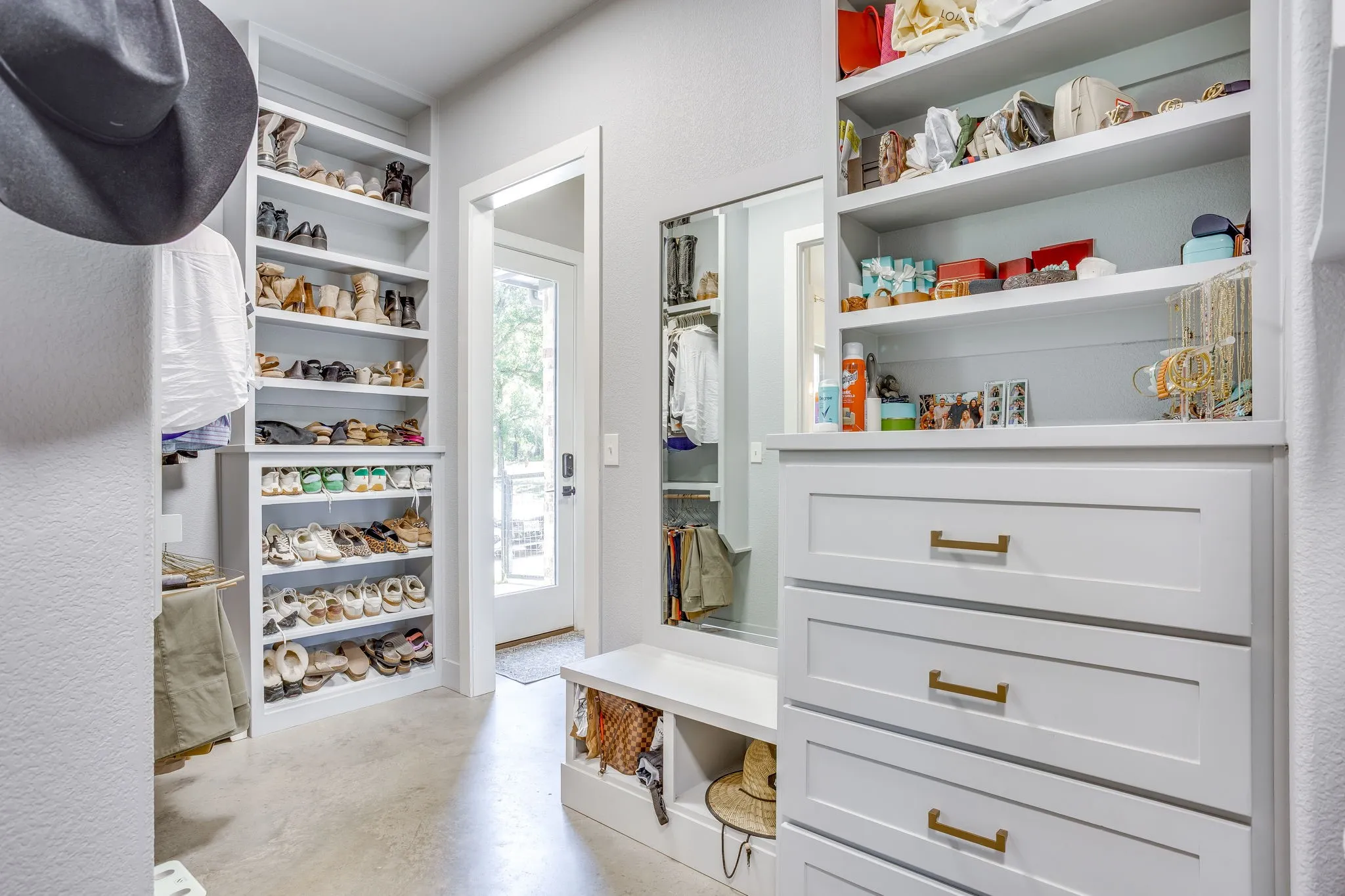 Built-in custom cabinetry, built-in shelving, and full-length mirror with access from the primary bath and the laundry room