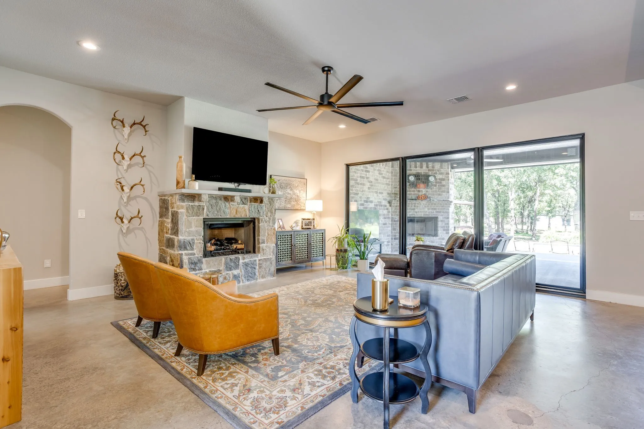 Stone fireplace with a hearth, recessed lighting, and a modern ceiling fan