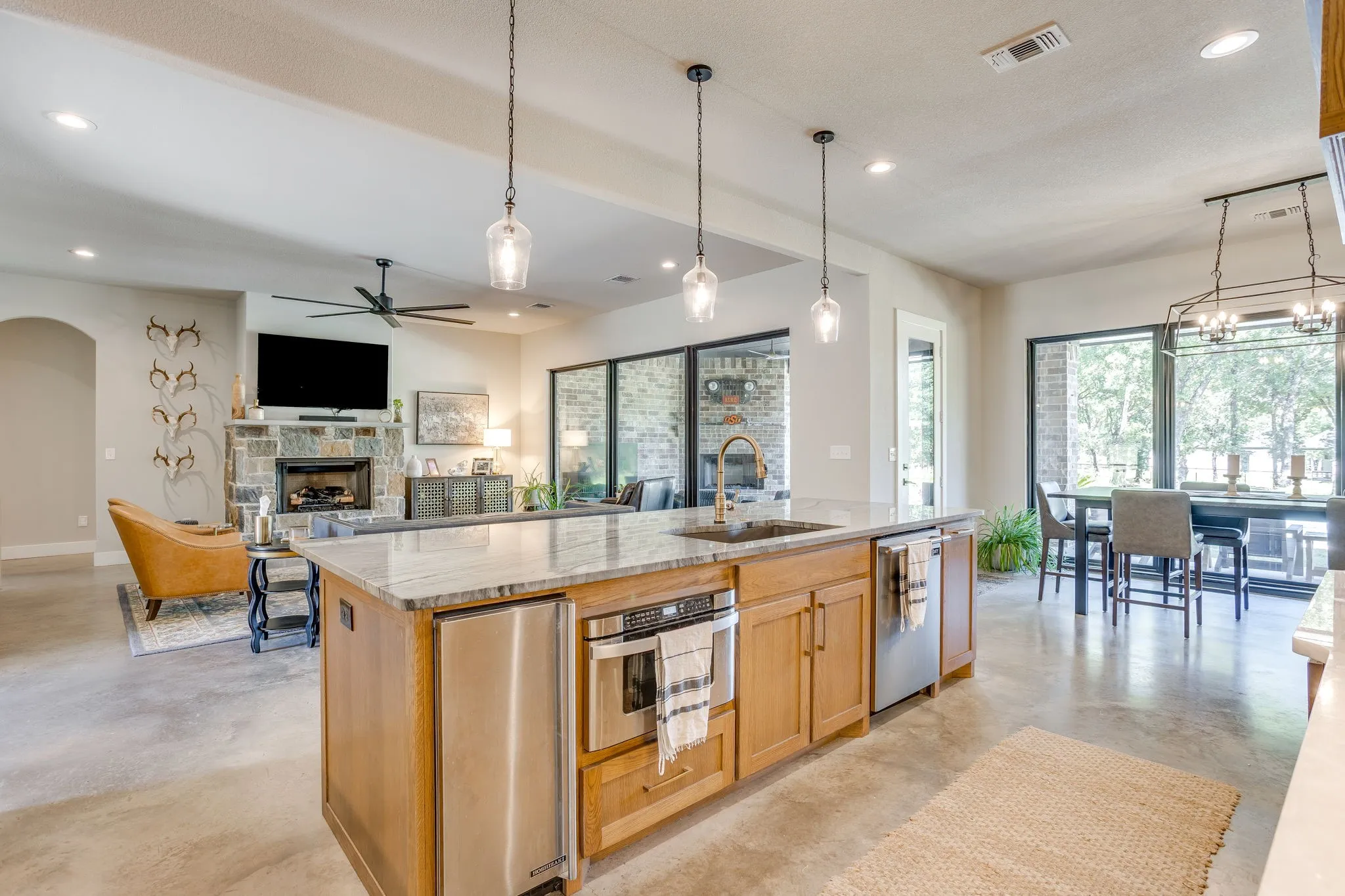 Expansive kitchen island with a stone countertop, integrated sink, built-in microwave drawer, and pendant lighting
